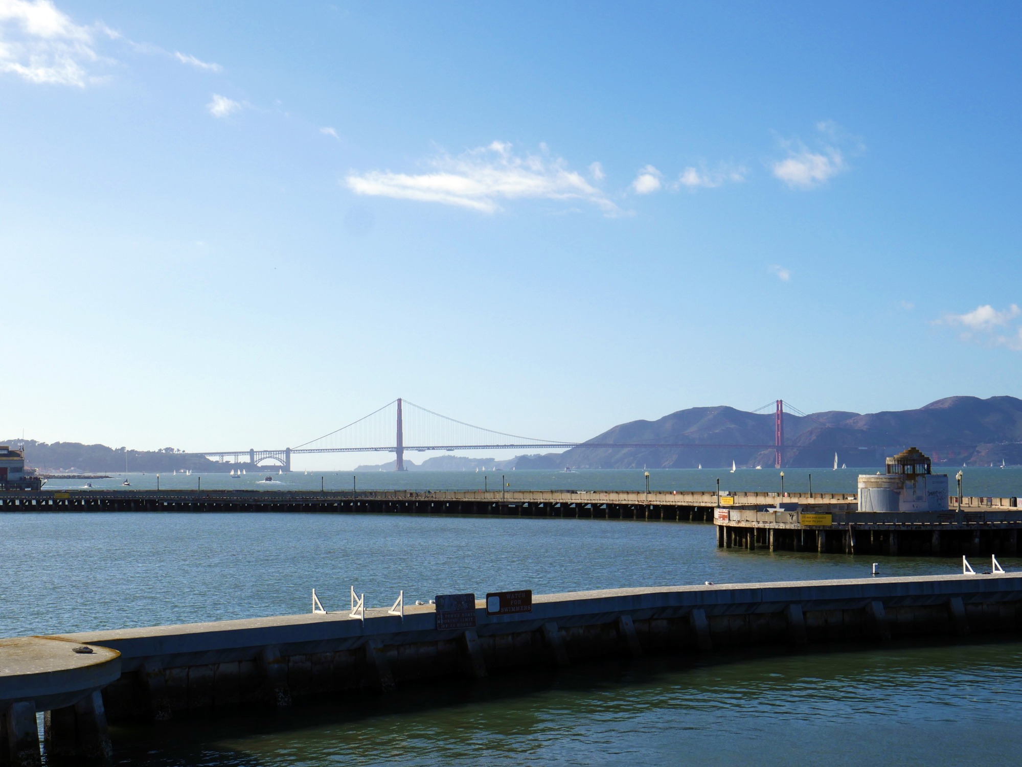 A view of the end of the Municipal Pier, with the Golden Gate bridge seen in the distance on a sunny day