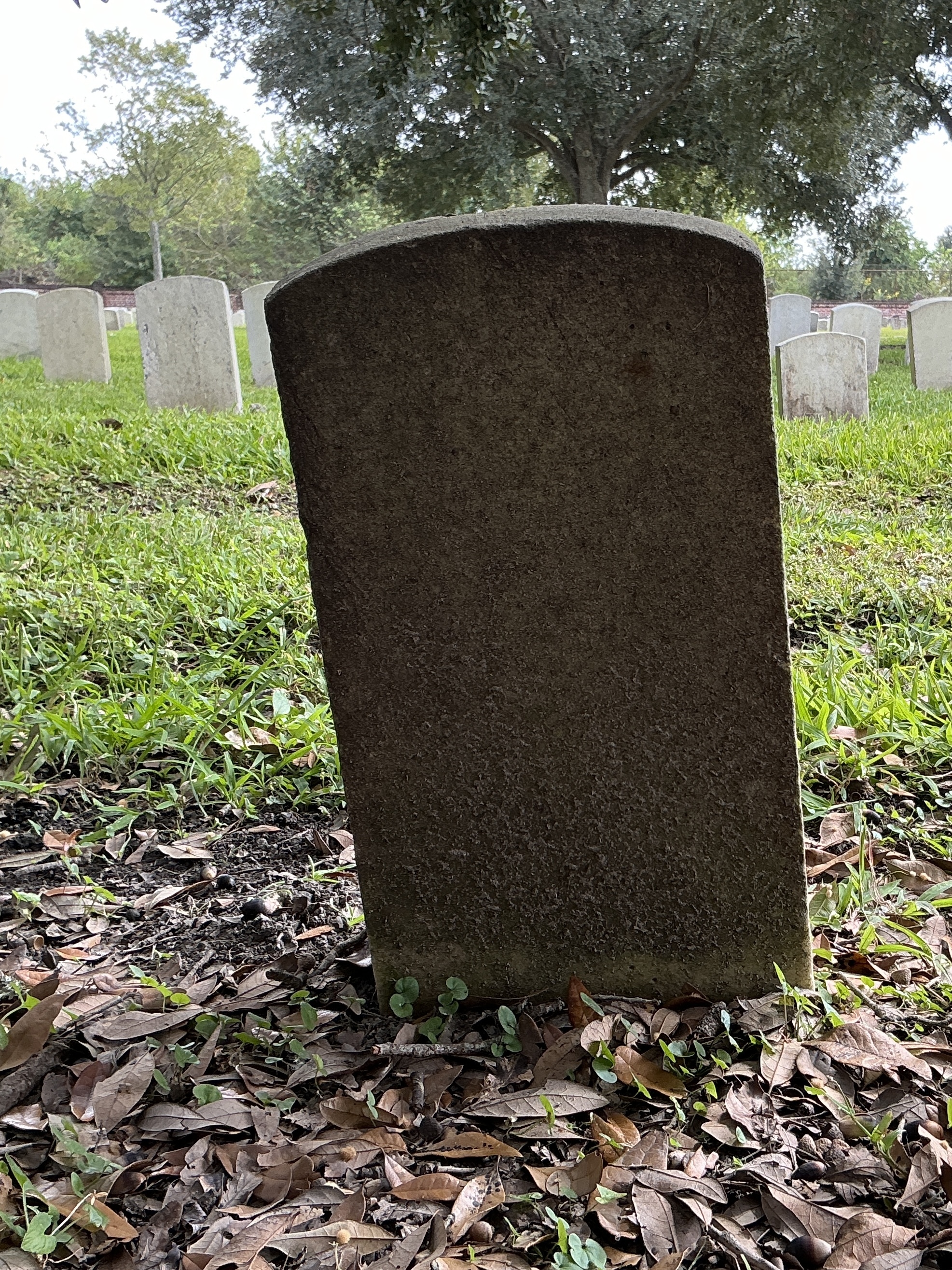Back of historic upright marble headstone with recessed shield face.