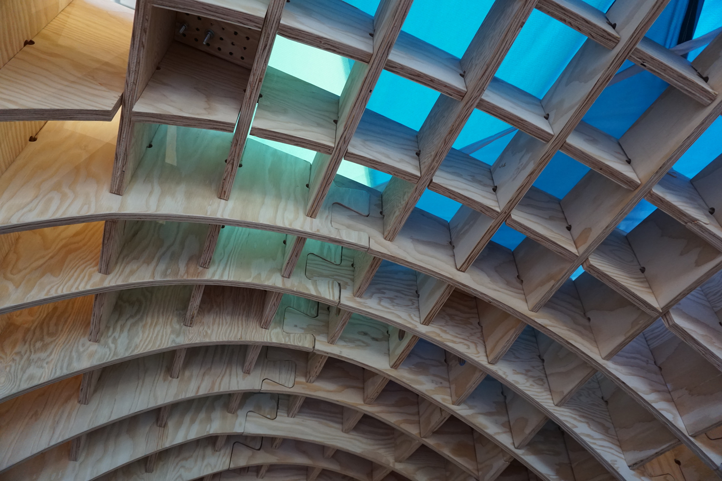 Interior shot of the parklet showing the wooden bracing and transparent tarps that project color inside when the light shines through. 