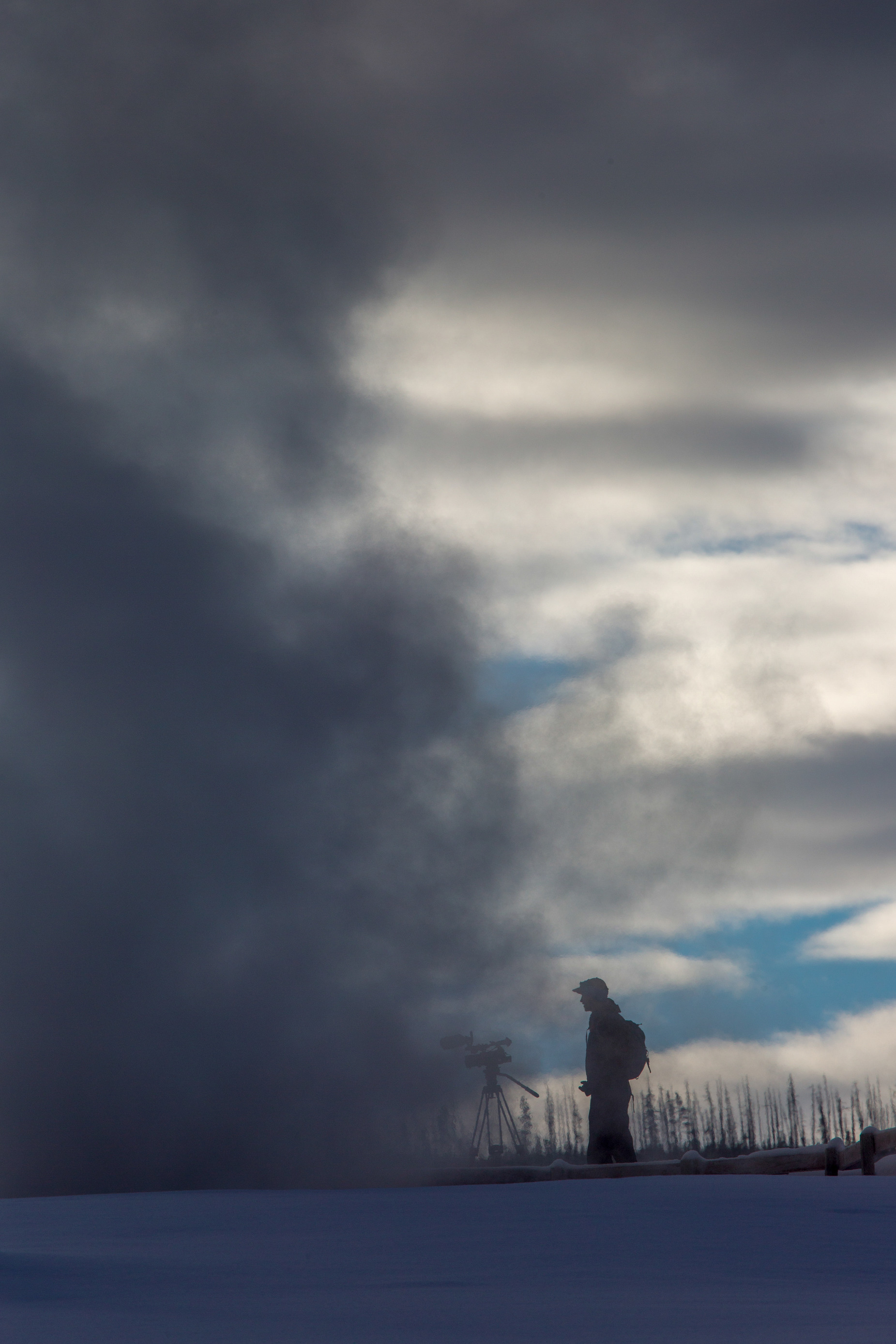 A man has video equipment set up pointed into a dense fog.