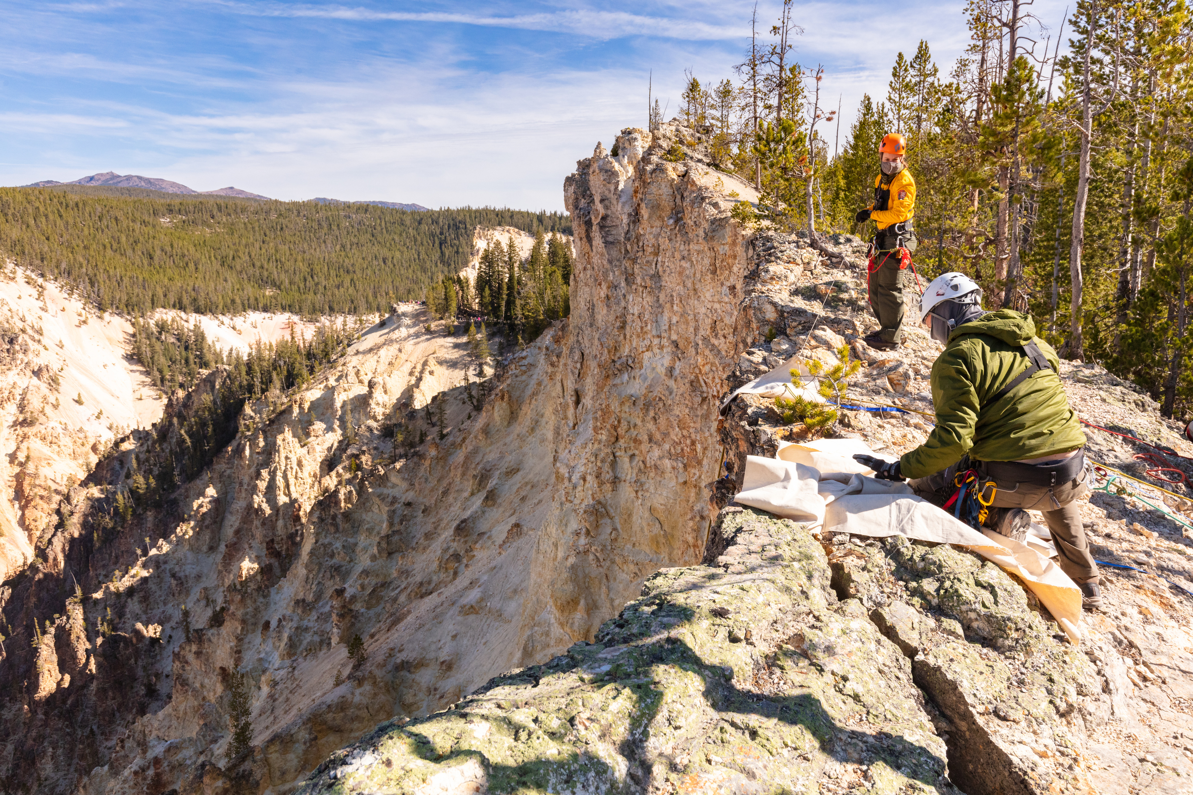 Two employees set edge protection on the top of a cliff