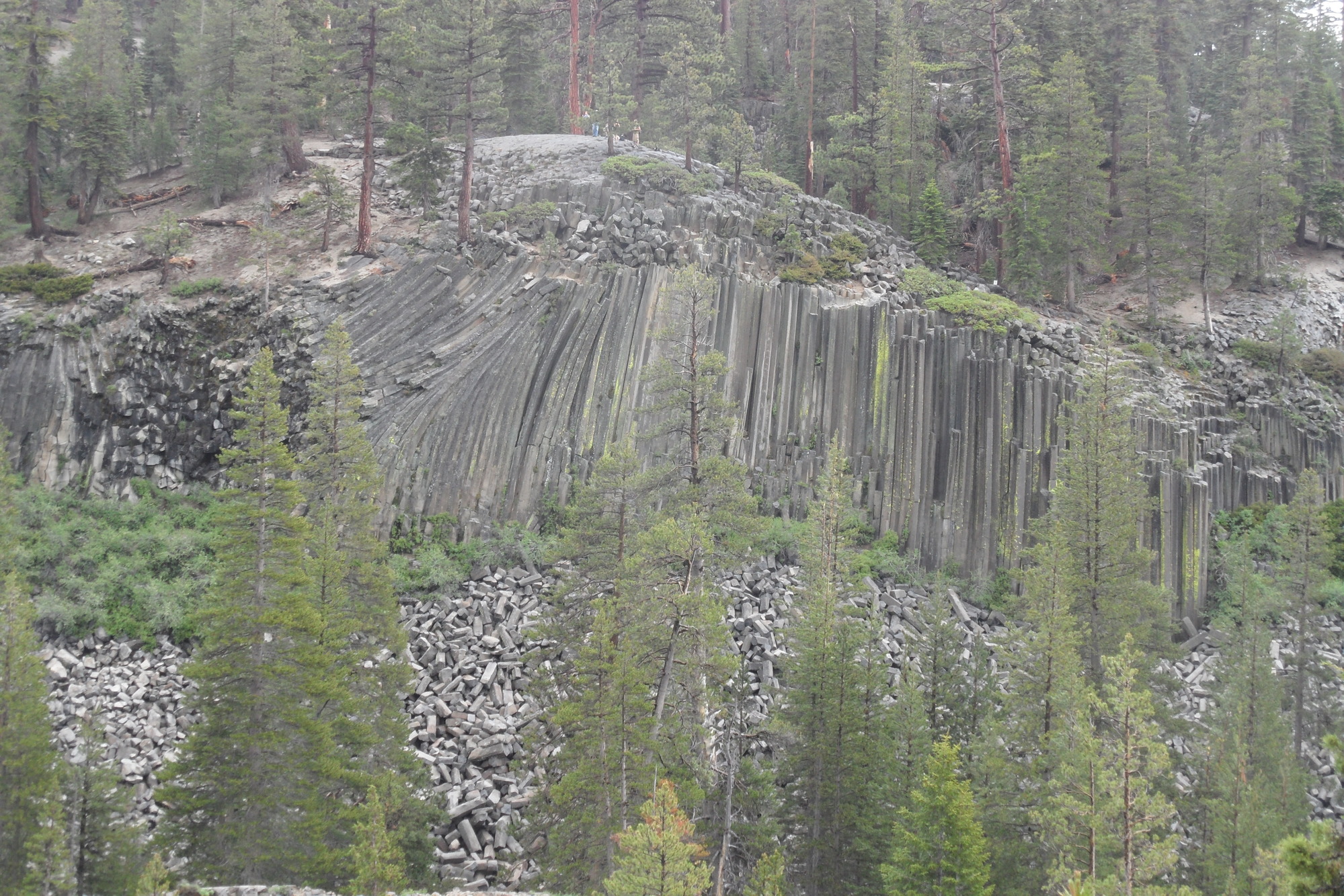 a wall of tall hexagonal tubes with some of them crumbling in pieces down the cliff 
