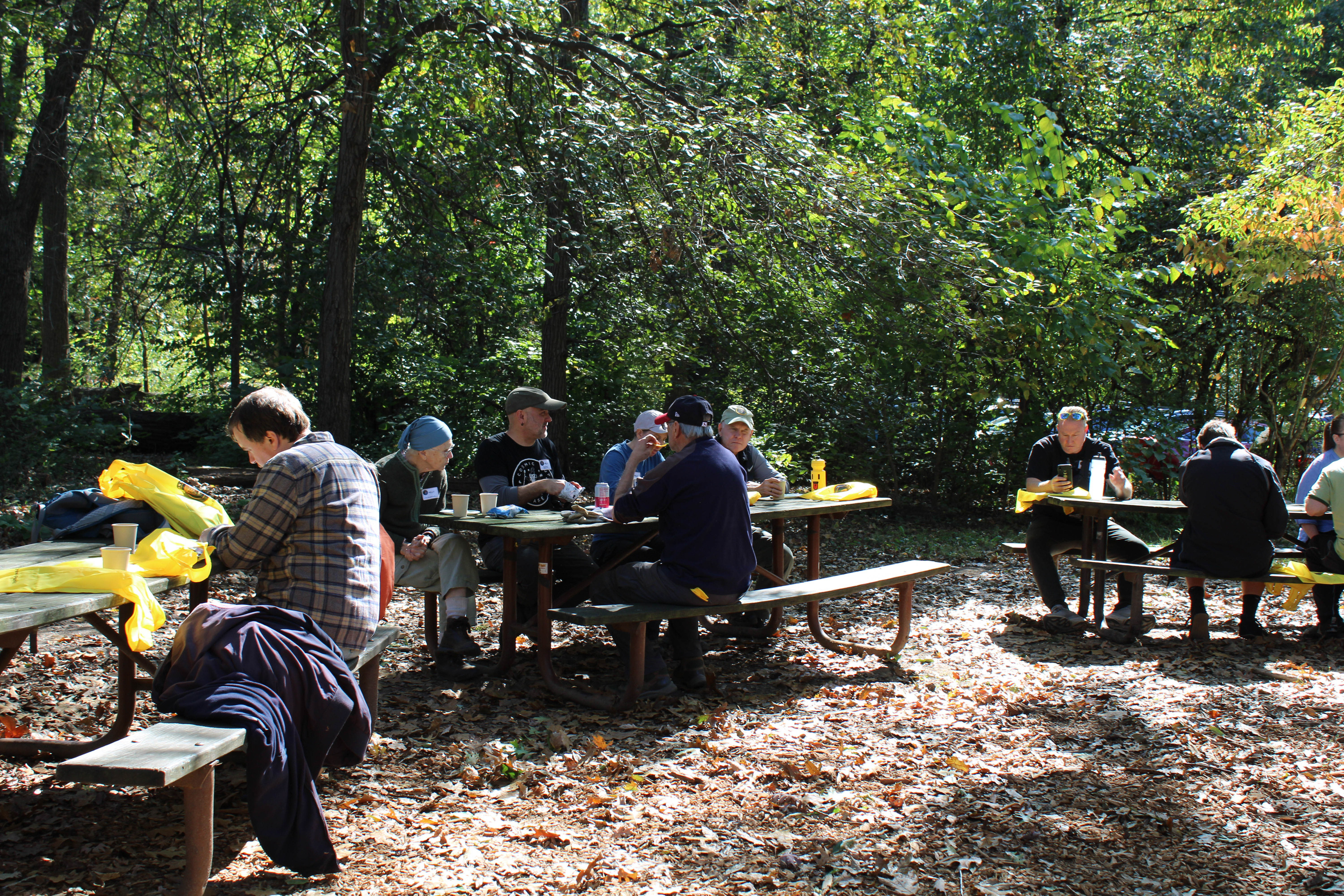 Volunteers seated at picnic tables, eating snacks, and waiting for the volunteer recognition event to begin. 