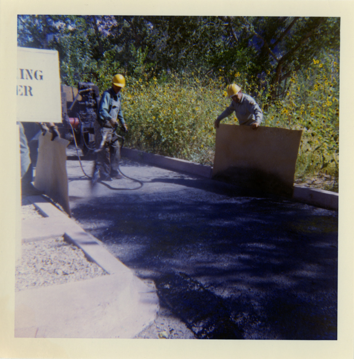 Men spraying top coat to road during chipsealing road repairs.