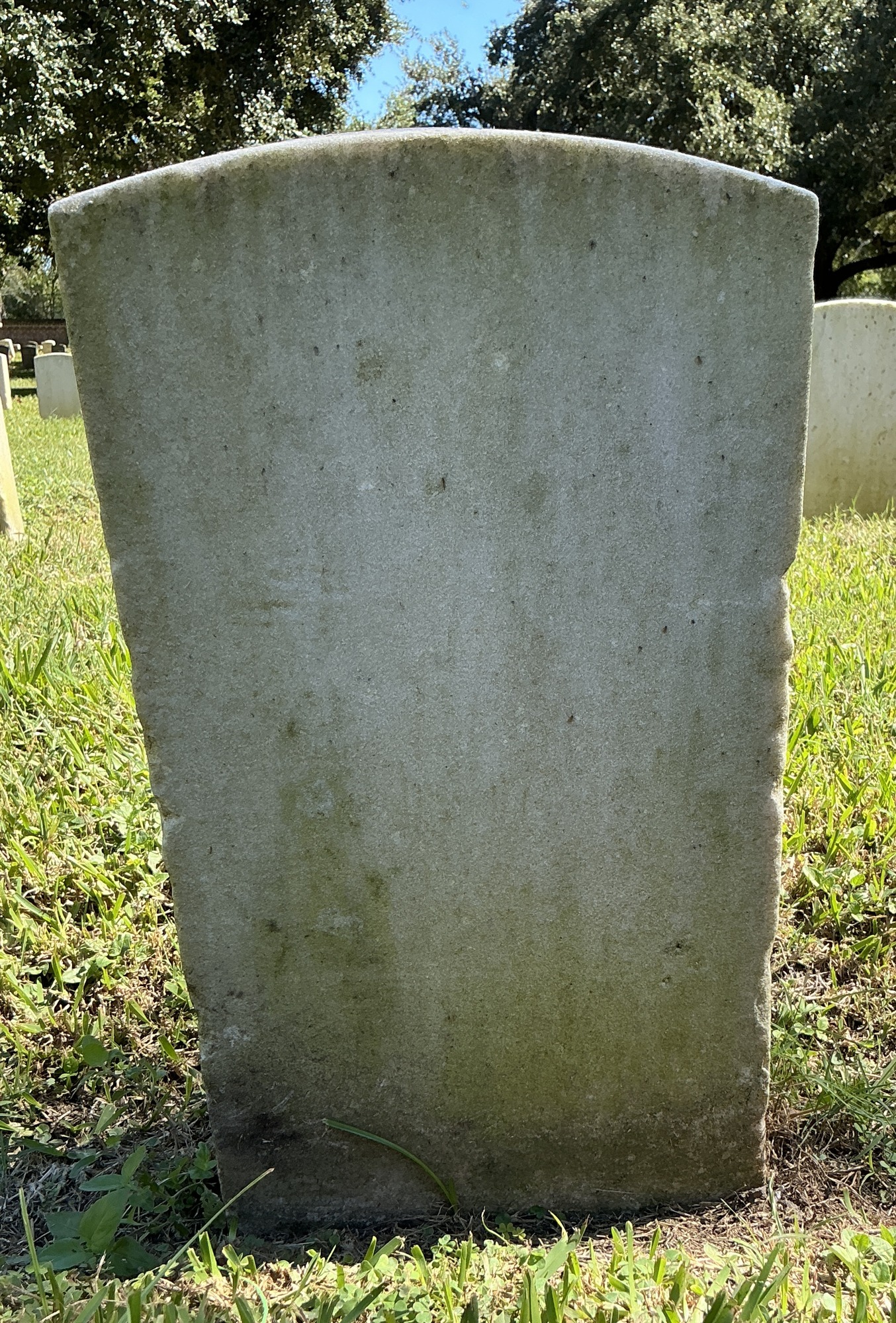 Back of historic upright marble headstone with recessed shield face.