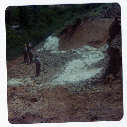 Men piling rocks on top of tarp during road work/repair in Kolob Canyon.