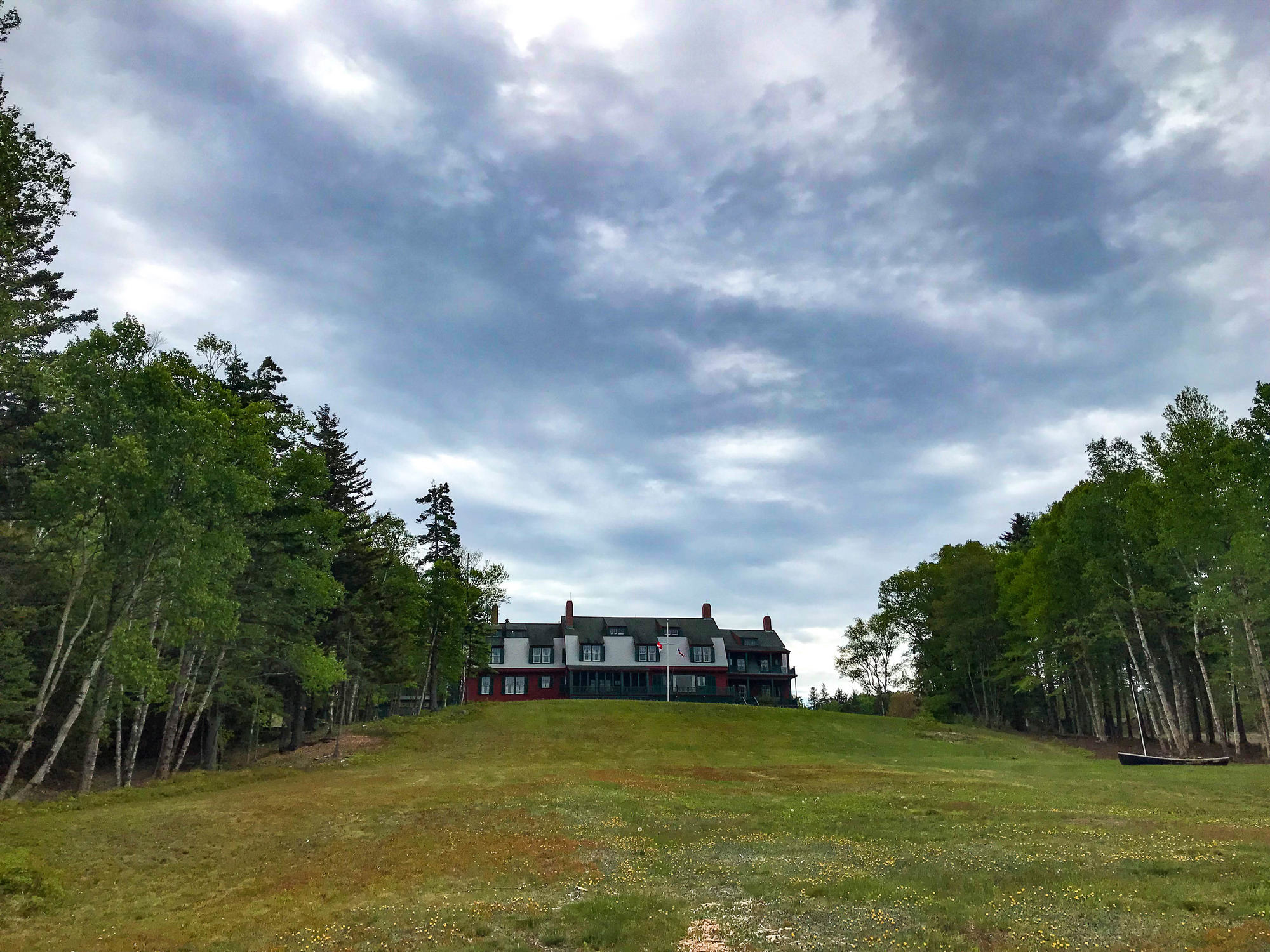 House on the top of a grass hill lined with trees