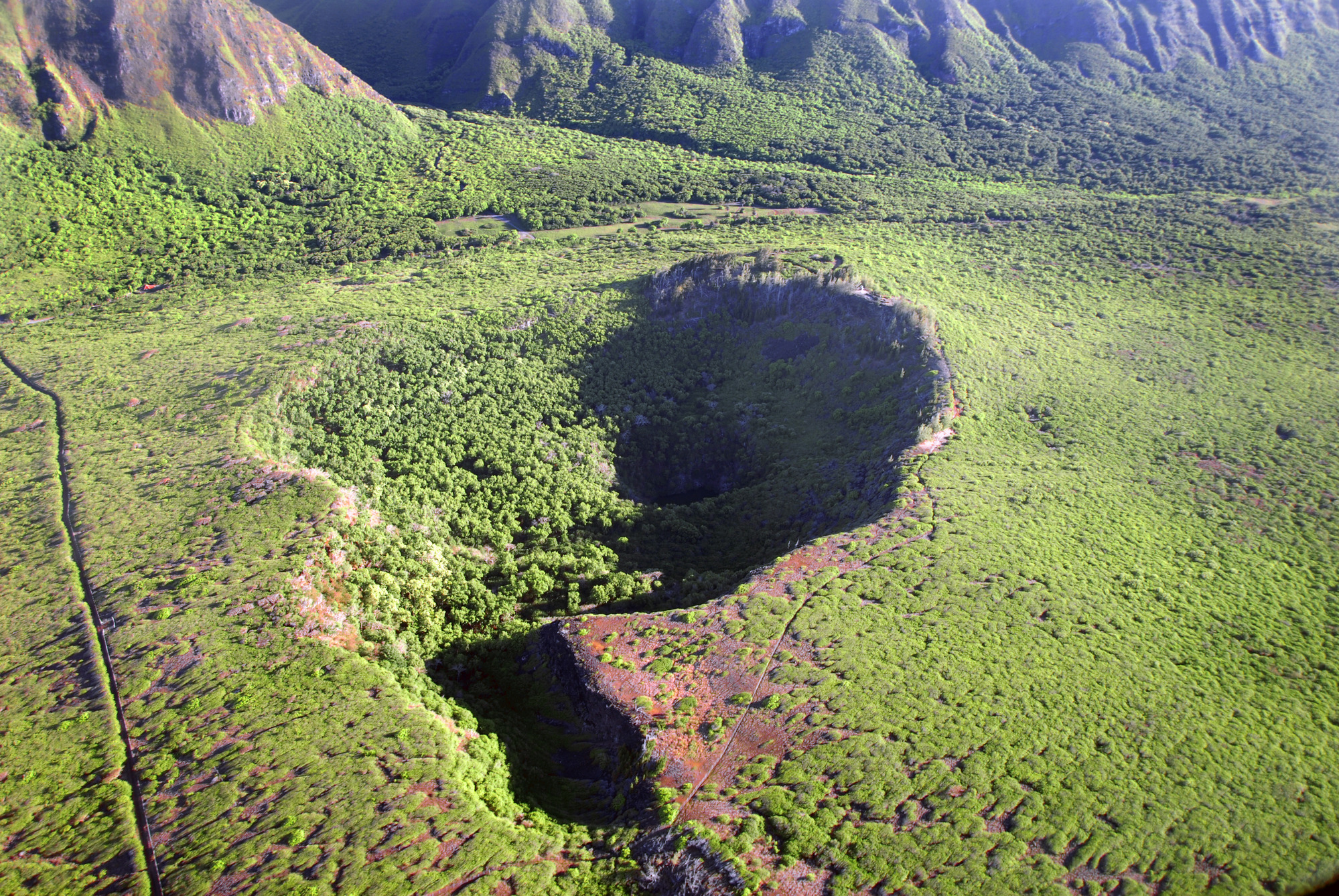 An aerial view of a crater below cliffs. 