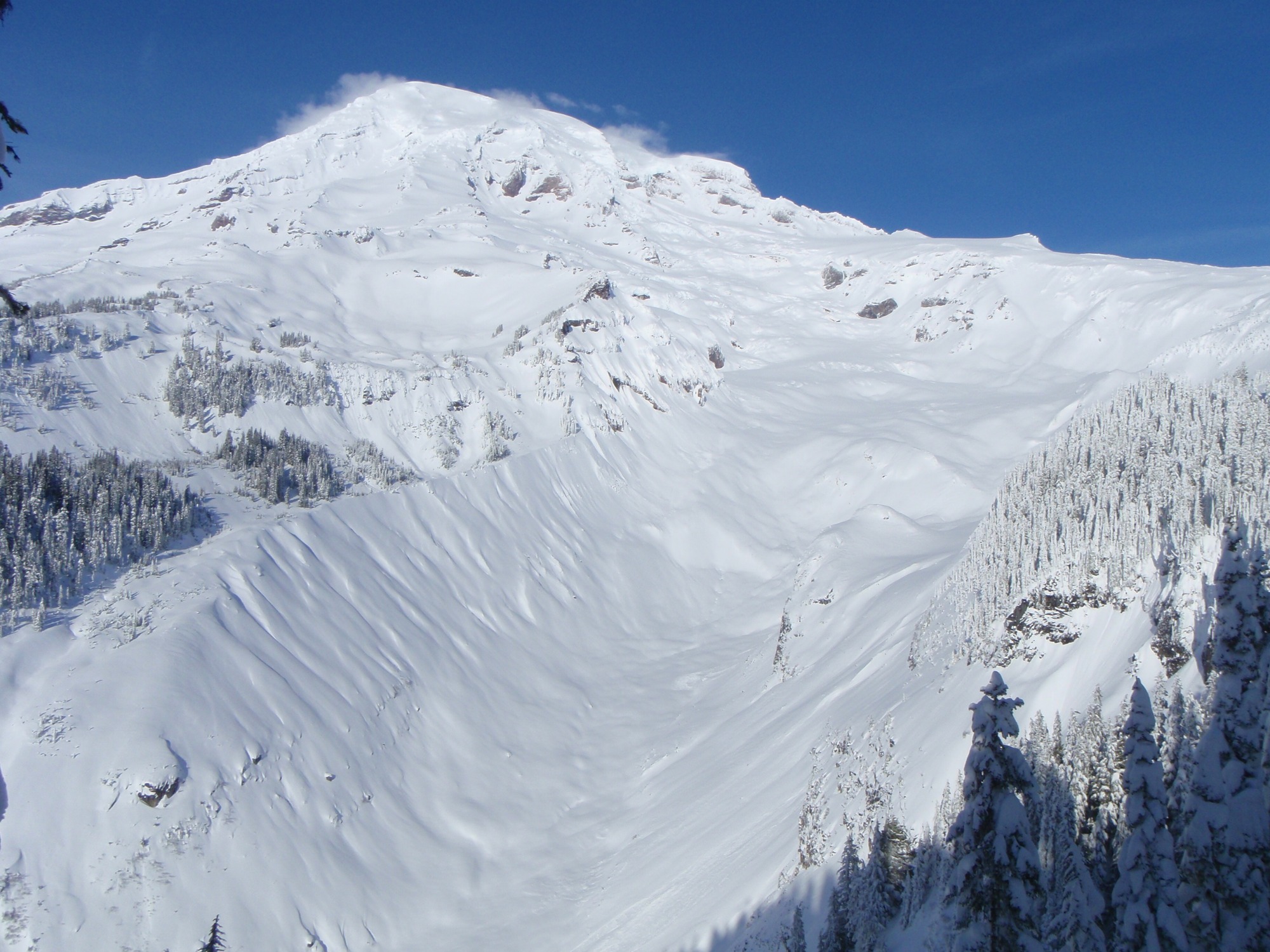 A blanket of snow covers a mountain and glacier-carved valley. 