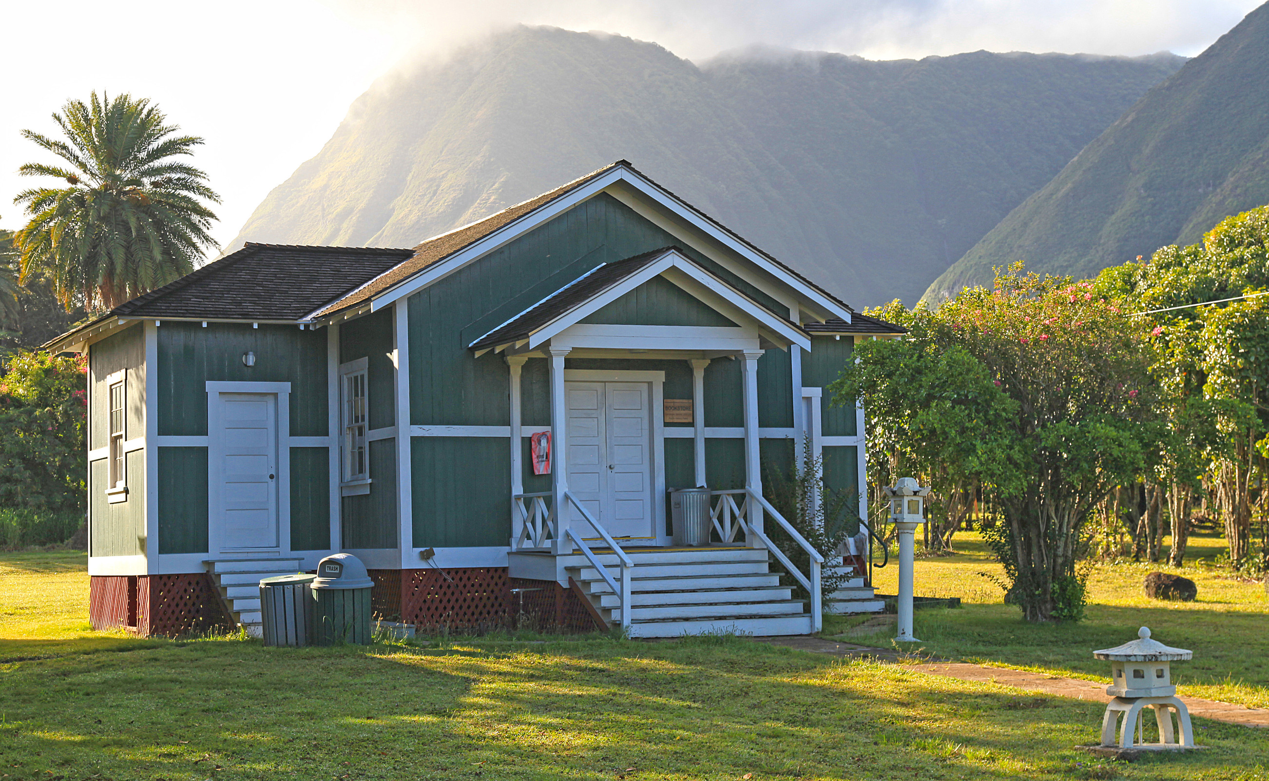 A teal building with white detailing and doors and a black shingled roof. 