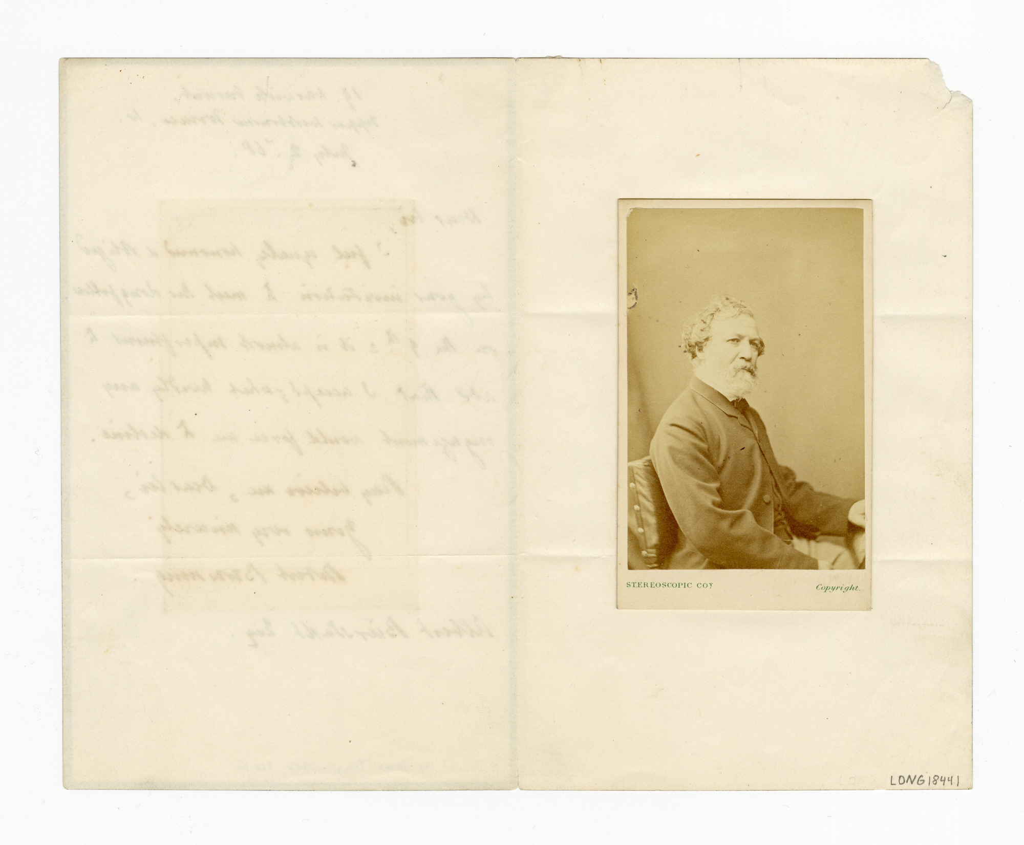 Manuscript letter with pasted-in photograph print of a man wearing a suit jacket and seated in a chair, looking towards picture right.