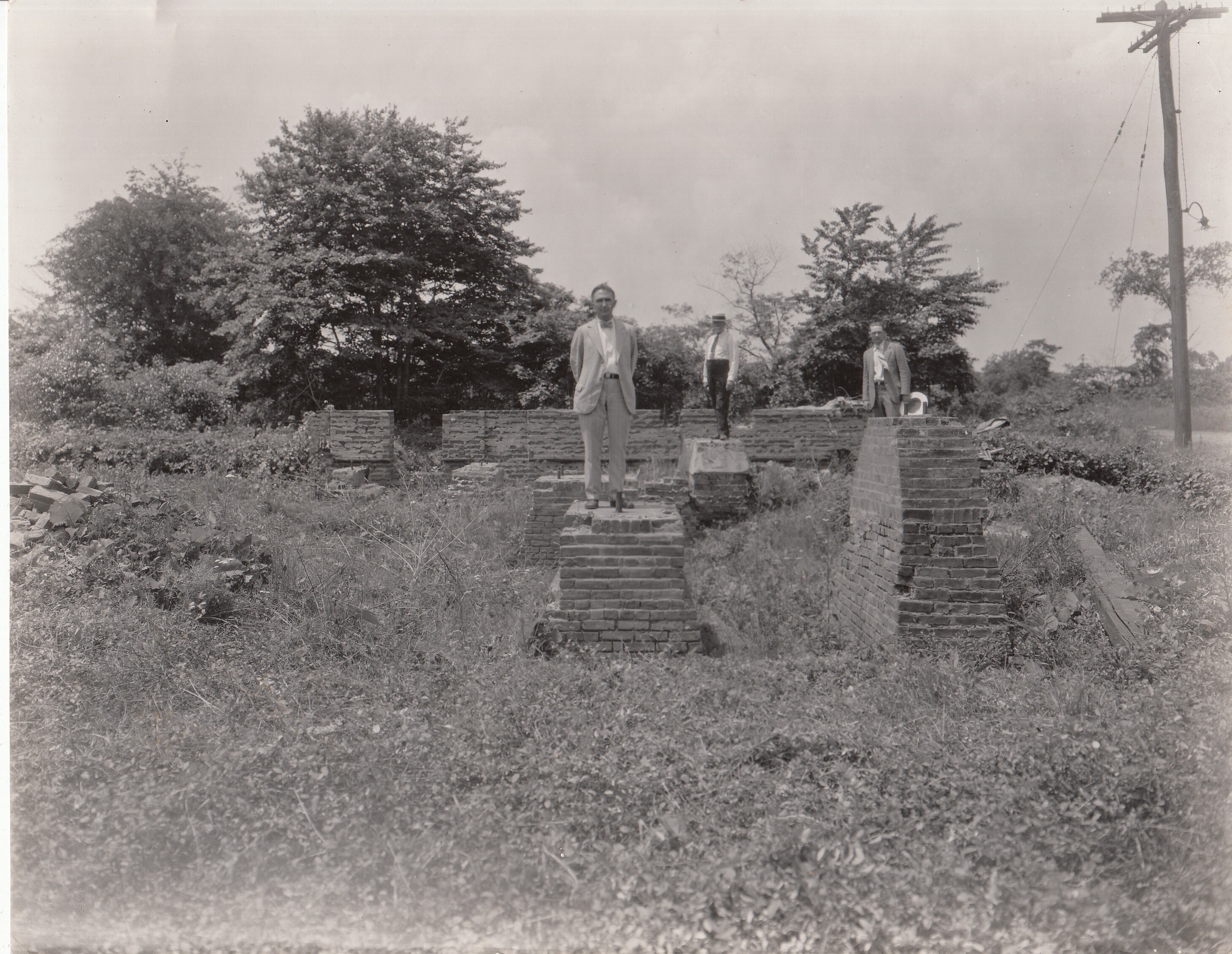 No. 3 engine room at Menlo Park site; Mr. Bishop on main bearing of large engine; Mr. Henry A. Campbell on foundation of original engine and dynamo; Mr. Bennett on chimney foundation.