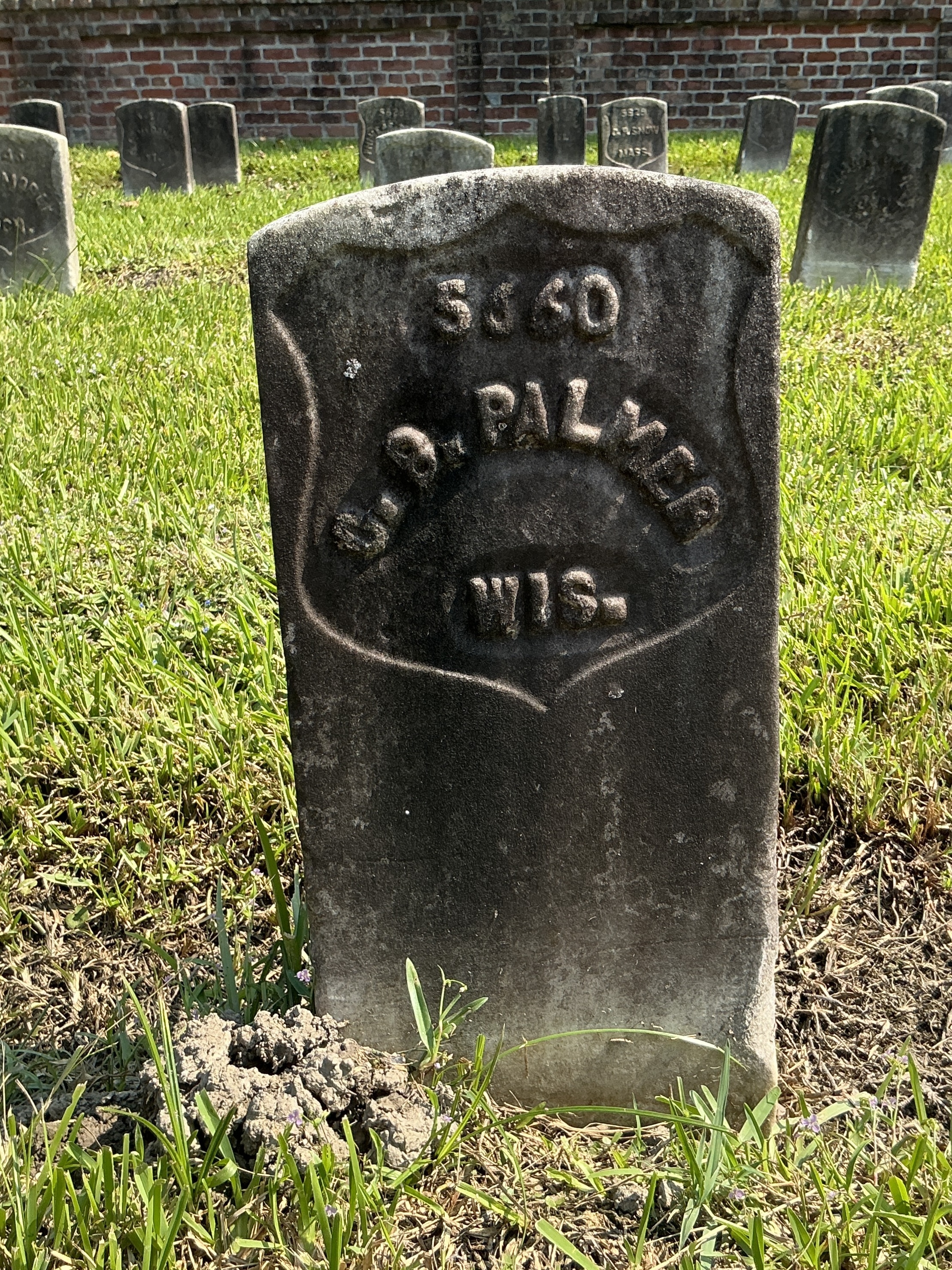 Front of historic upright marble headstone with recessed shield with recessed lettering face.