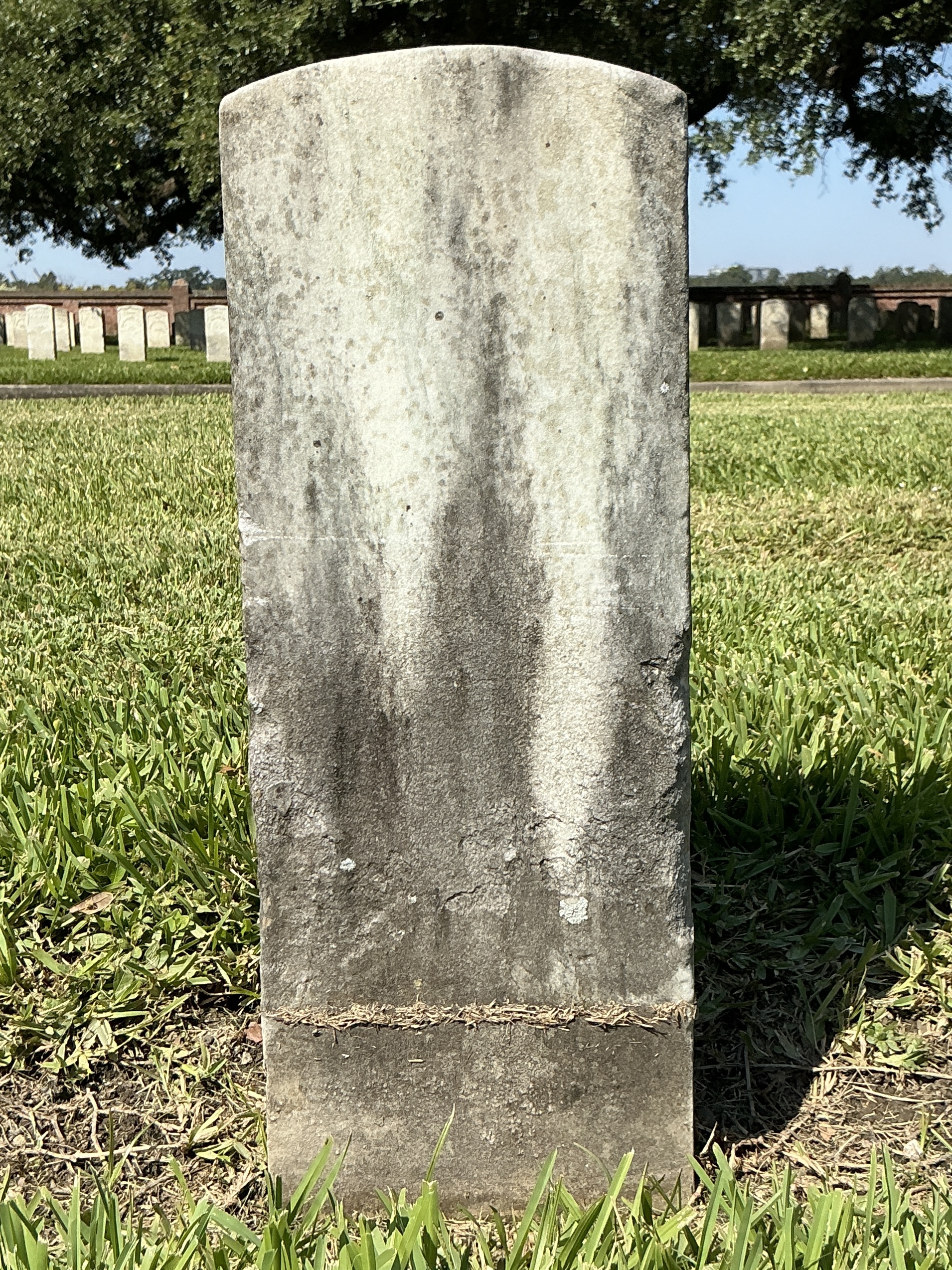 Back of historic upright marble headstone with recessed shield with recessed lettering face.