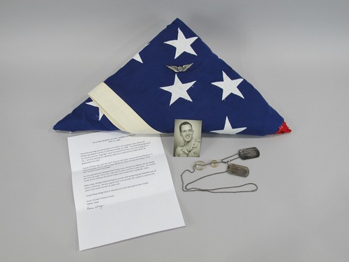 This folded American flag was presented to the widow of Dennis "Mike" Michael Phillips (KIA 05/31/1969) after his death in Vietnam. It was placed at the Wall in June of 2019, along with his Army Aviator wings (which are attached to the flag), his charred dog tags and wedding rings on a chain necklace, a wallet-sized black and white photograph of Captain Phillips from his Officer Candidate School graduation, and a letter written by his wife, Karen.