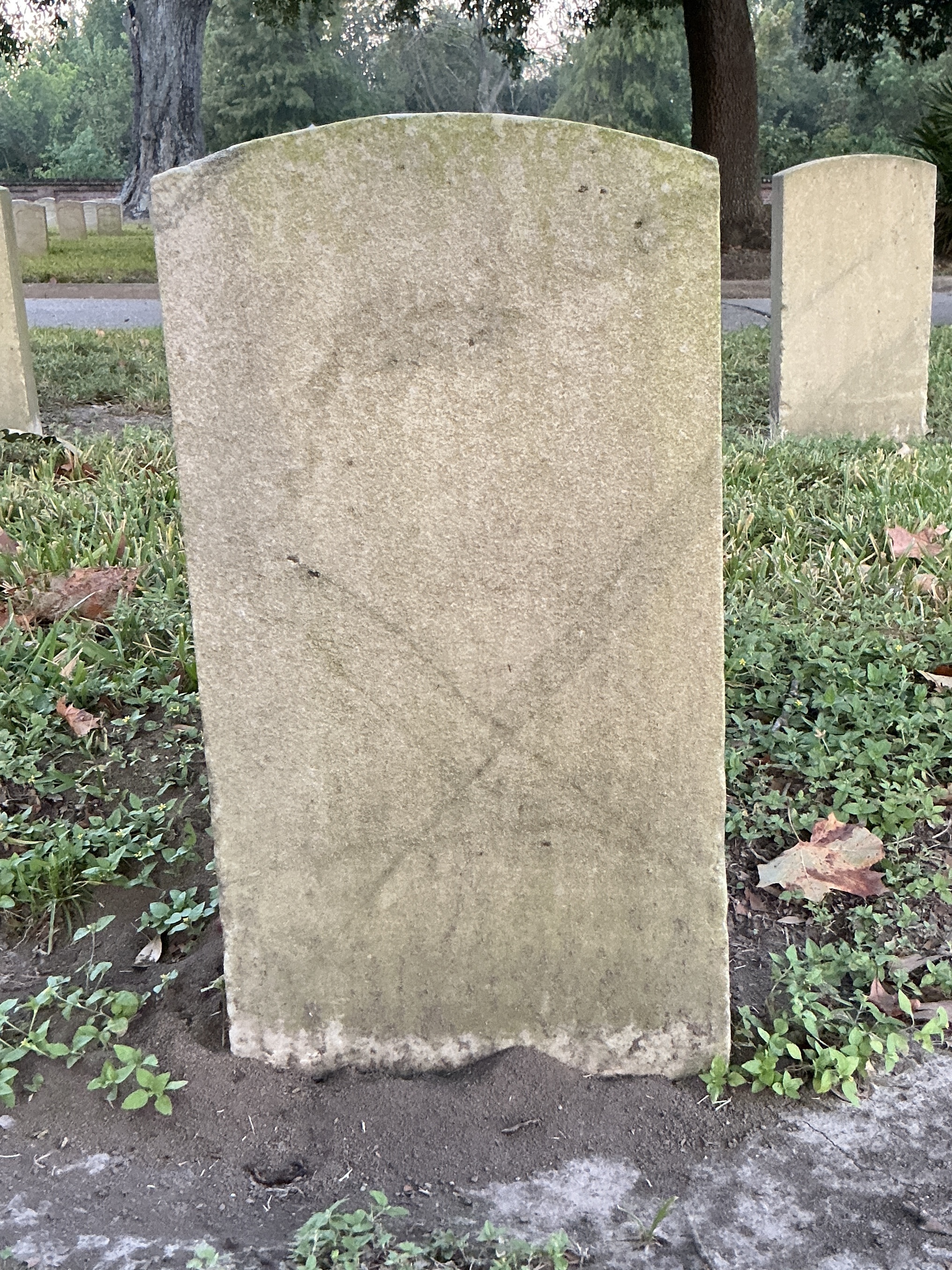 Back of historic upright marble headstone with recessed shield face.