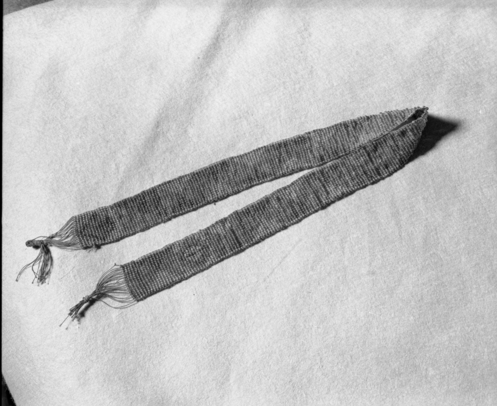 Mrs. Donald Segerstrom Collection. Object: Paiute (?) beaded section. Dimensions: 22 1/4". Materials: Transparent red, green and dark blue beads on black thread. Technology: Single thread loomwork. Photographed by Michael Dixon. Catalogued by Craig Bates and Barbara Beroza. Yosemite Collections, National Park Service. 1/83.