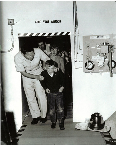 A family accompanies an officer through a narrow passageway