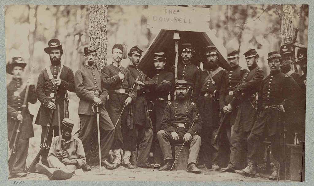 9th Massachusetts Volunteer Infantry at Camp Cass near Fort Cass, Arlington Line Defenses, Virginia. An African American contraband in Federal uniform can be seen sitting on the ground in the image.