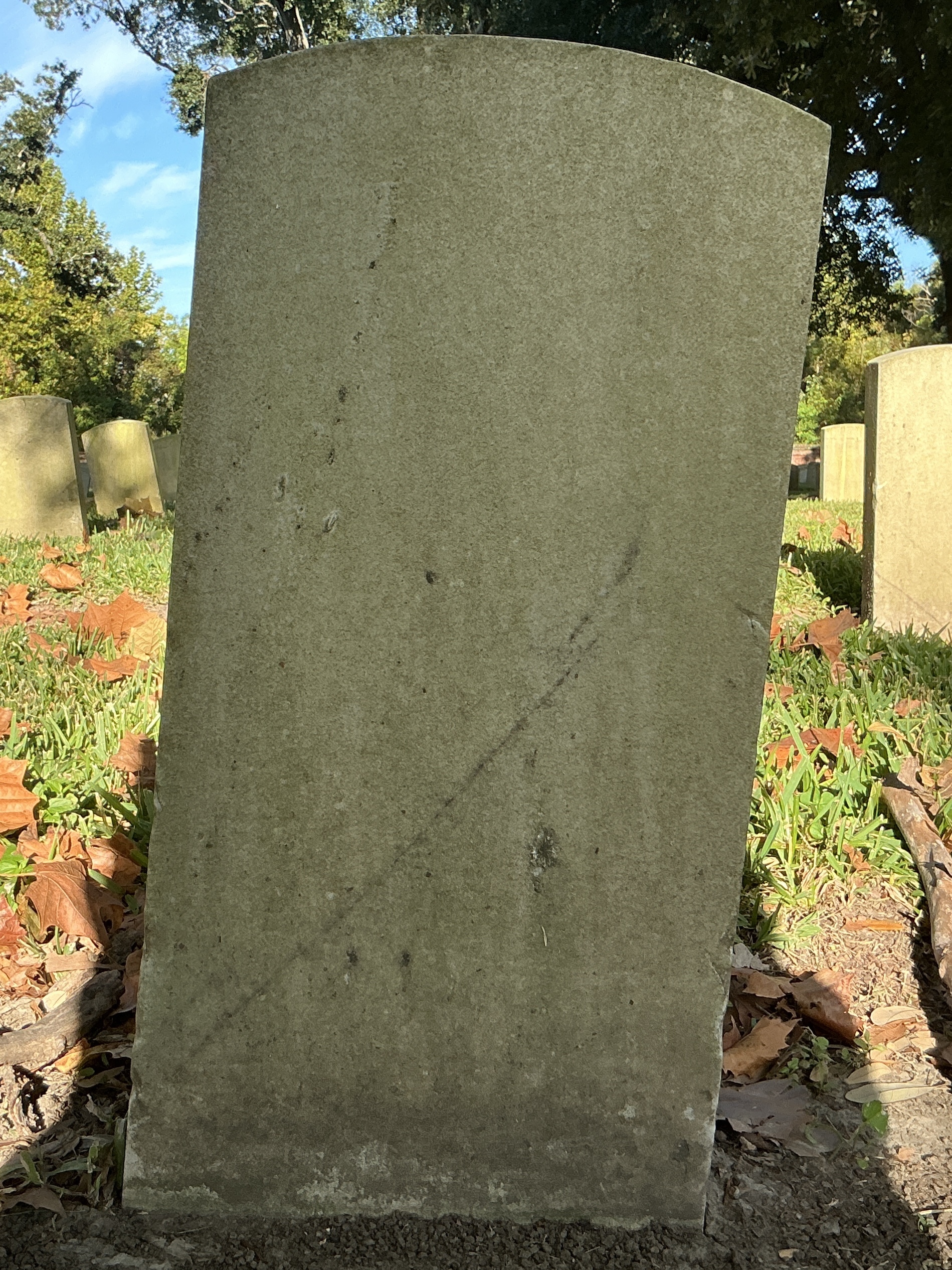 Back of historic upright marble headstone with recessed shield face.