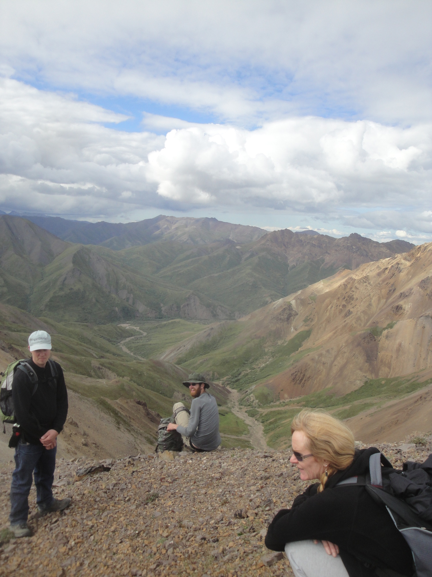 three people resting on a mountaintop