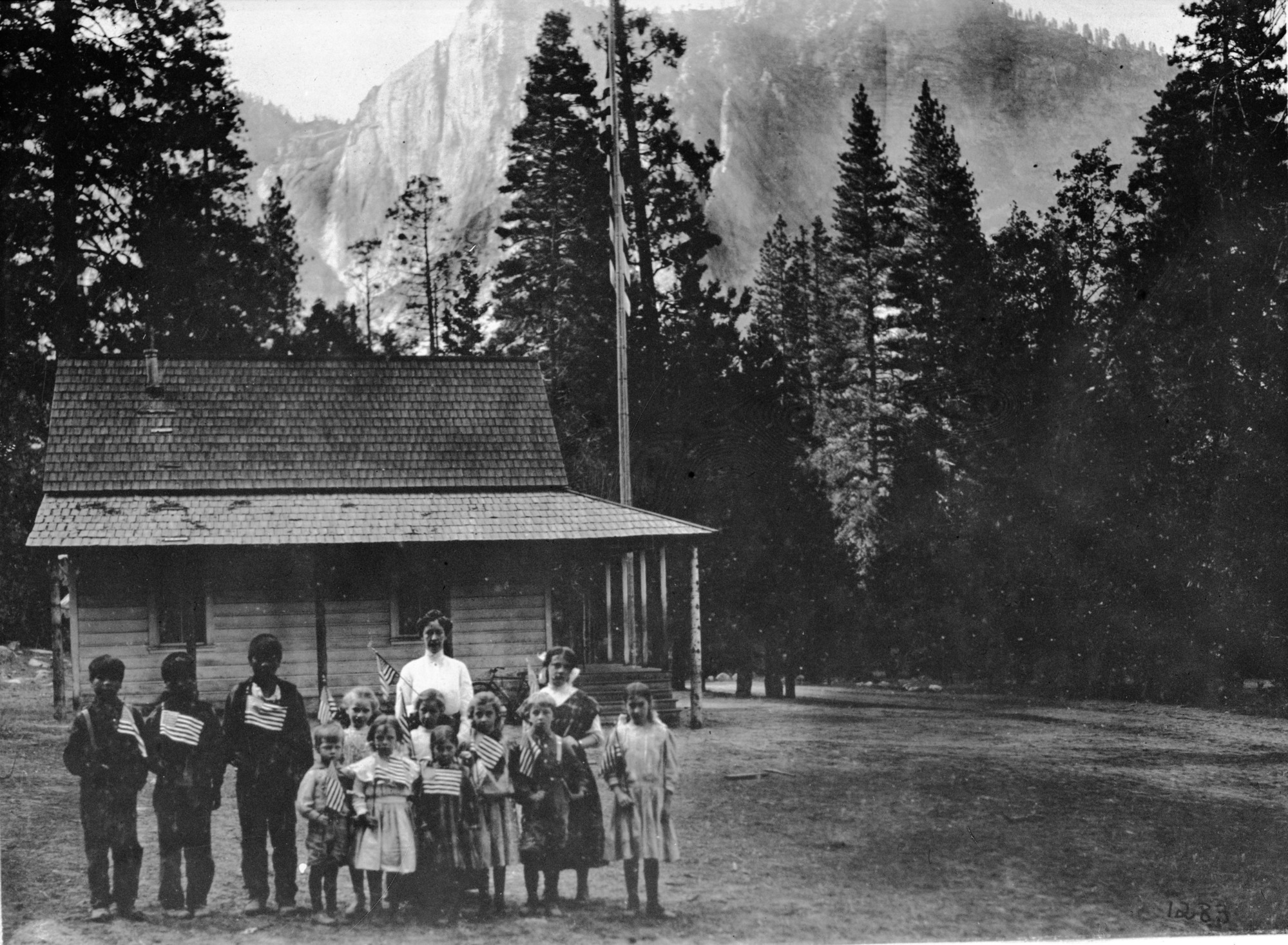 Early day schoolhouse with group of students. Left to right: Frank Dick, Fred Dick, George Dick, Lawrence Sovulewski, Evelyn Tucker, Alice Degnan, Miss Dexter (teacher), Ellen Boysen, Mildred Sovulewski, Lillian Park, Harlow Park, Ruth Degnan, Grace Sovulewski (Frank Dick might be Fred and Fred might be Frank). I.D. by Craig Bates, August 22, 1989, based on school registers in Yosemite Museum collection and YM cnt. no. YOSE 21119. copied by D.C., copied February 1936