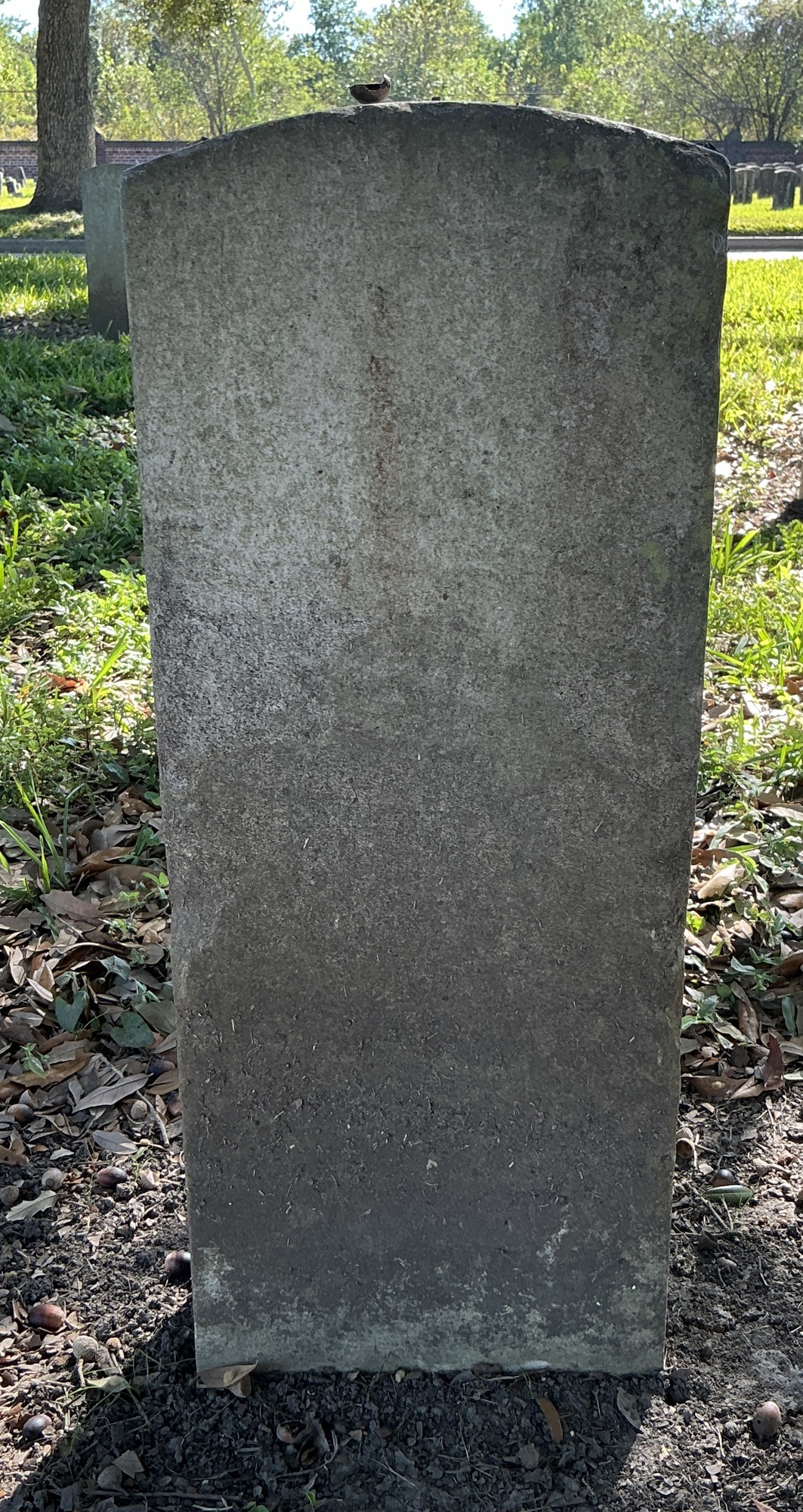 Back of historic upright marble headstone with recessed shield face.