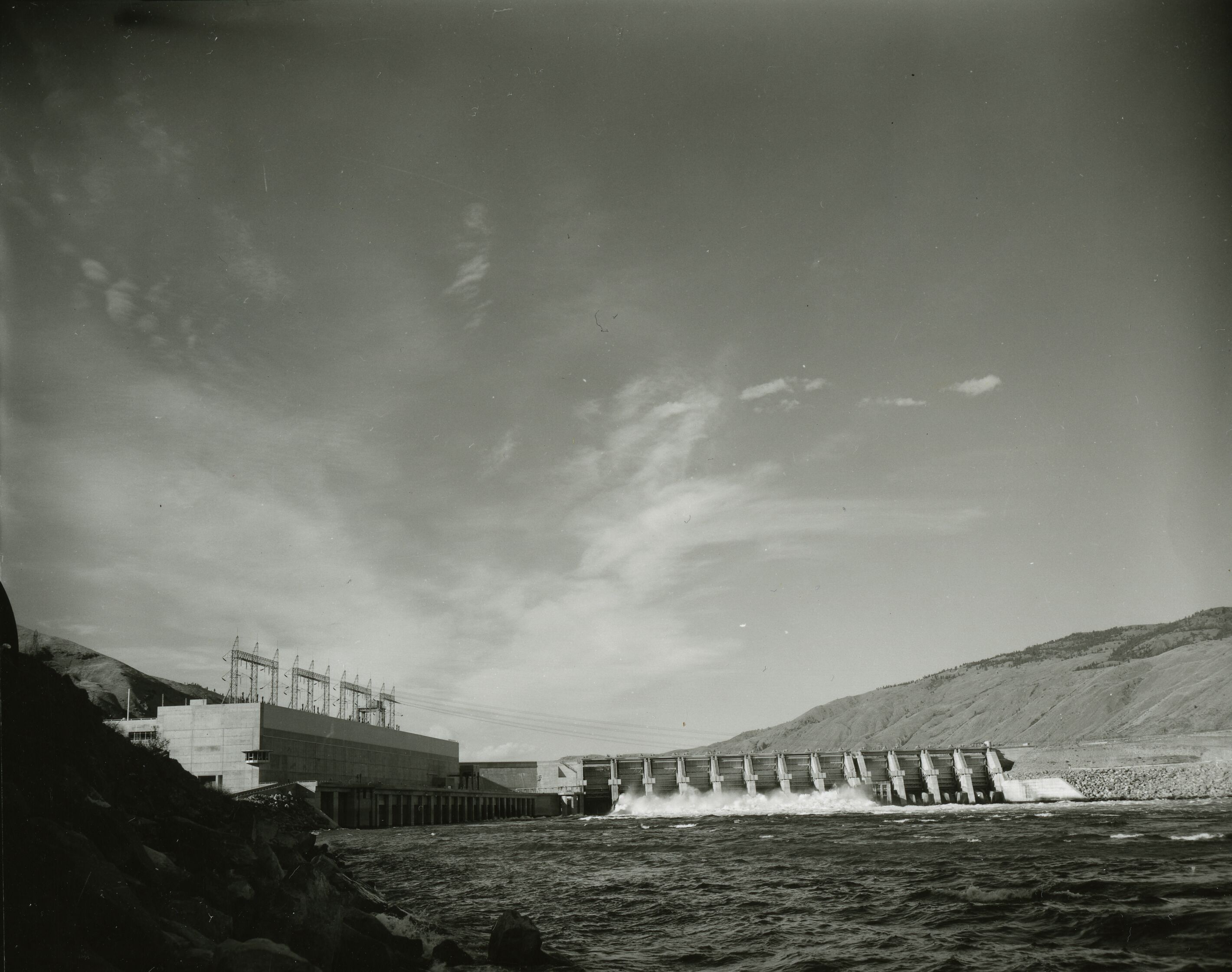 A dam with water spilling out into a lake.