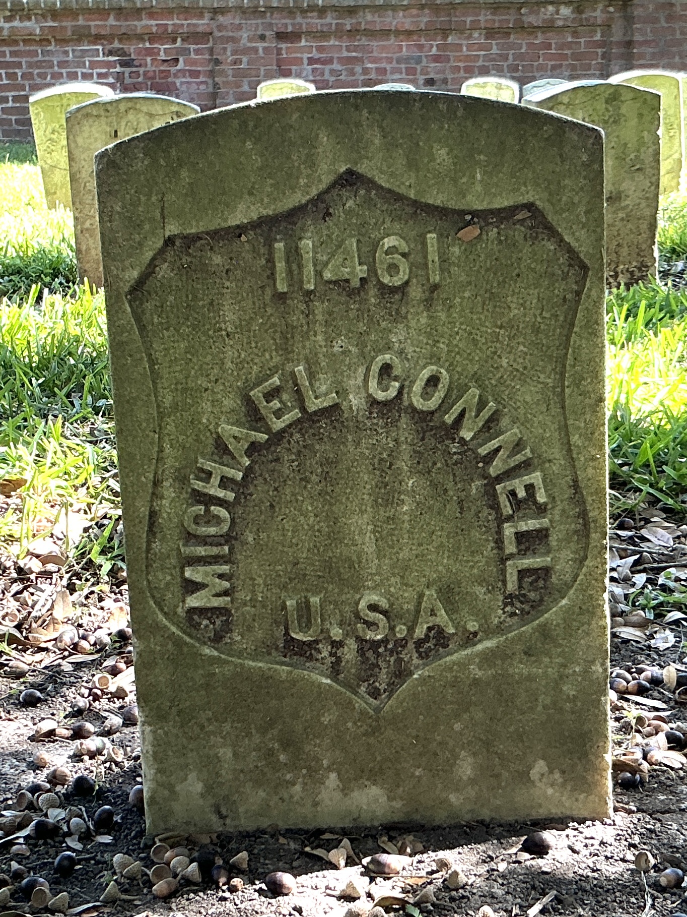 Front of historic upright marble headstone with recessed shield with recessed lettering face.