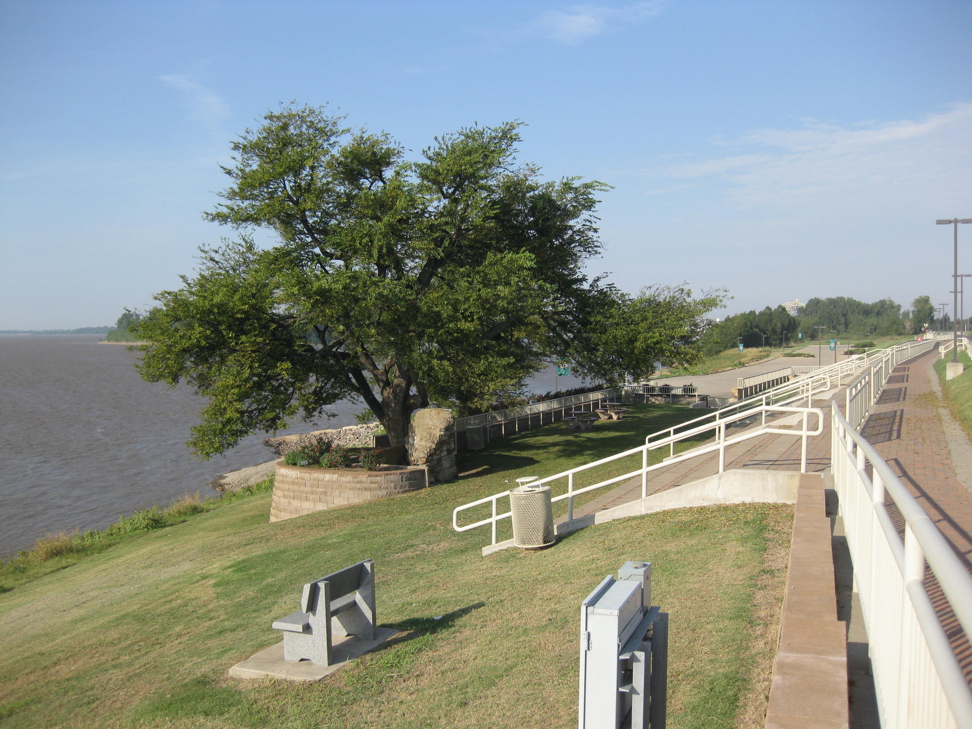 A bench next to a sidewalk next to a body of water.