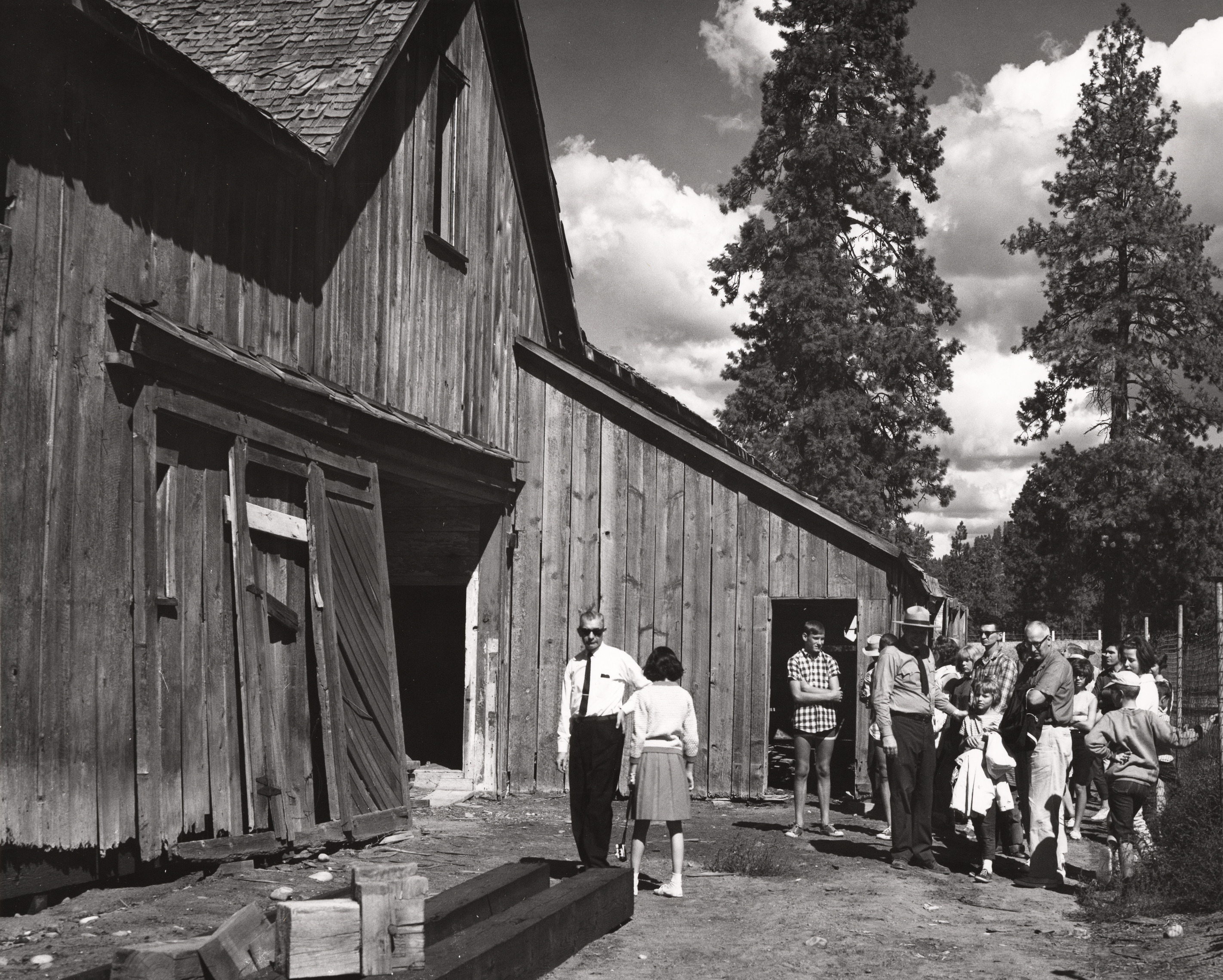 Black and white photograph of a crowd of people in front of a barn