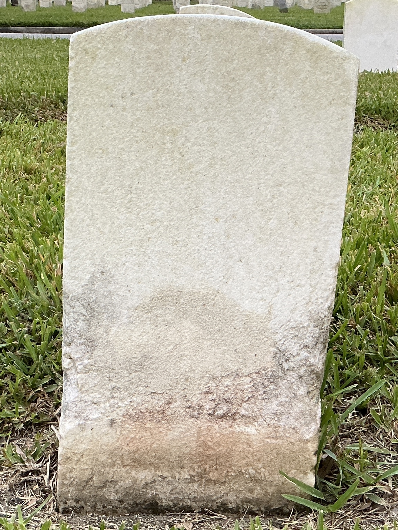Back of historic upright marble headstone with recessed shield face.