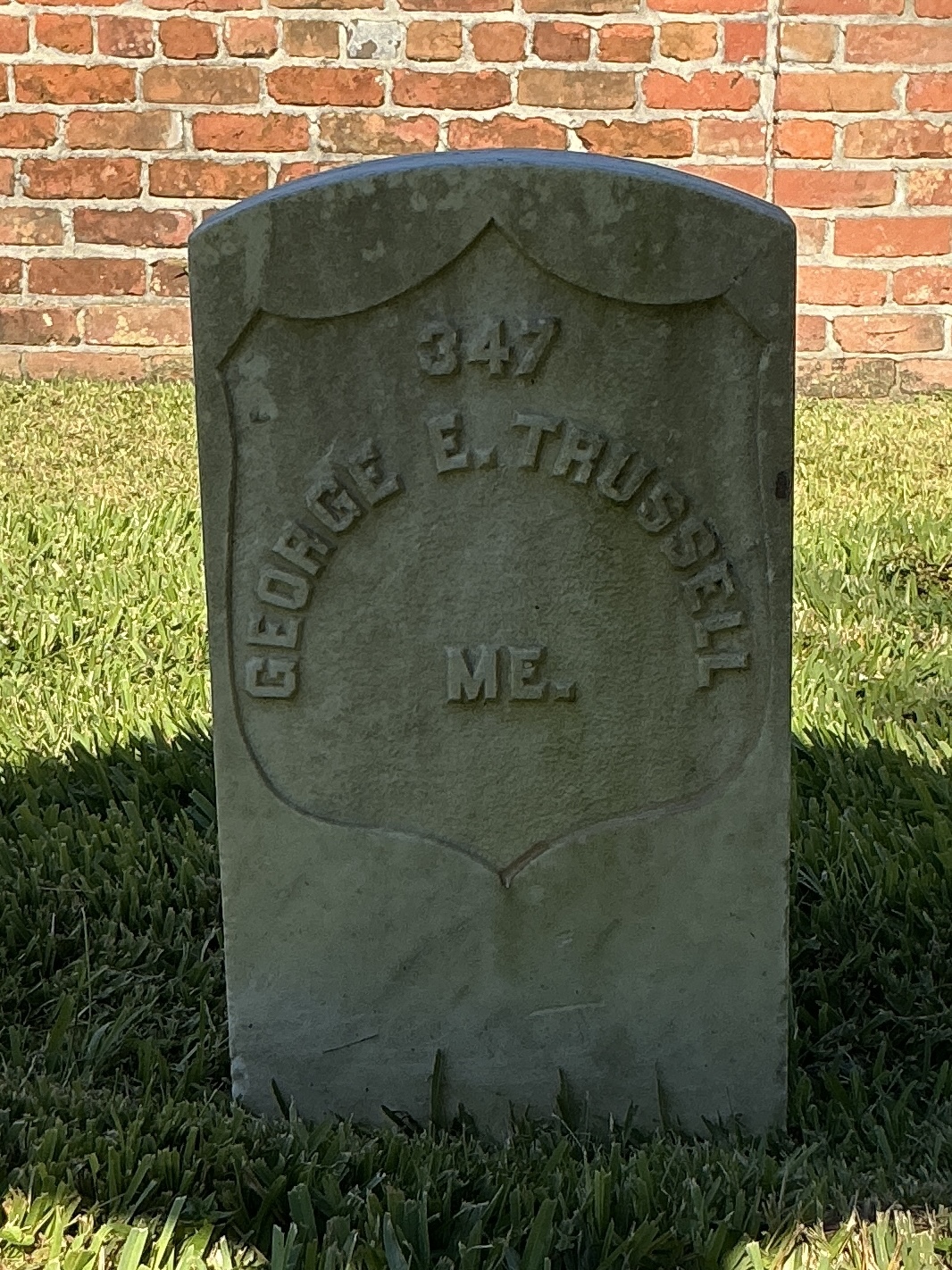 Front of historic upright marble headstone with recessed shield face.