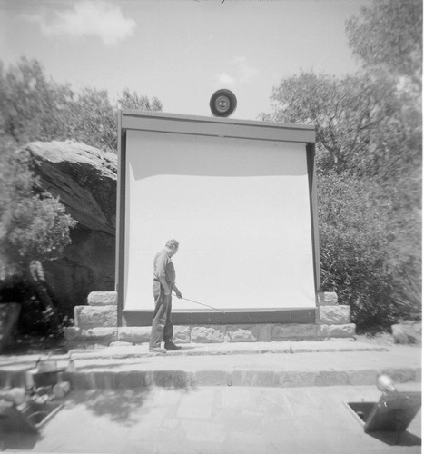 Man standing in front of the South Campground Amphitheater screen and projector.