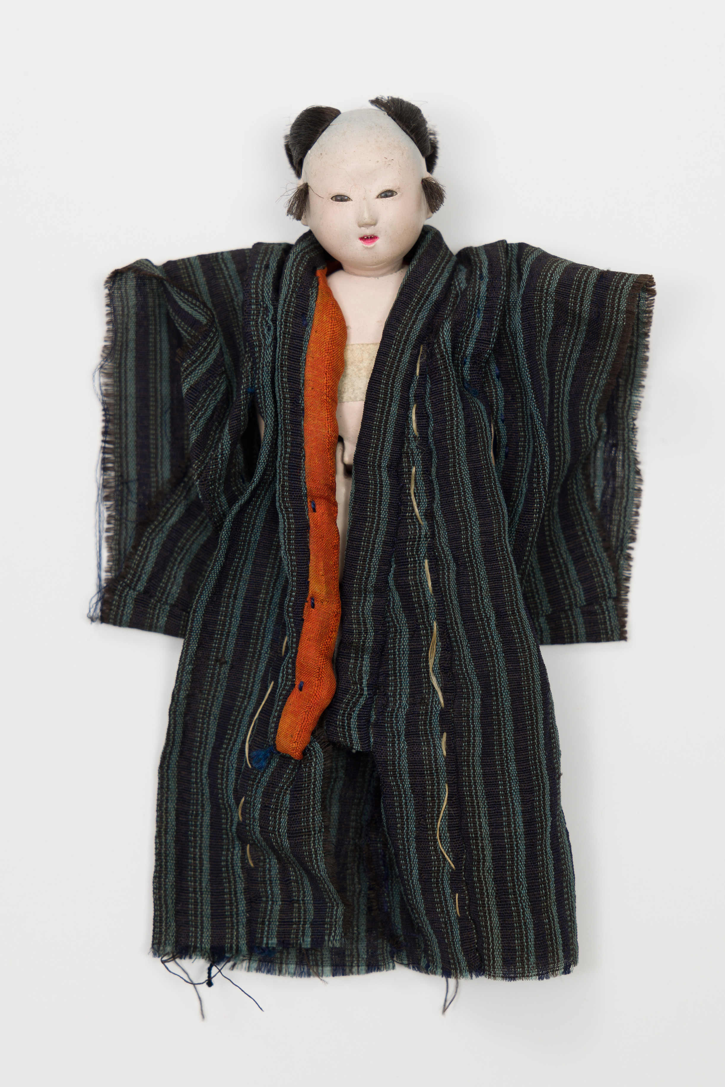 Small doll wearing blue kimono with red lapel on left side.