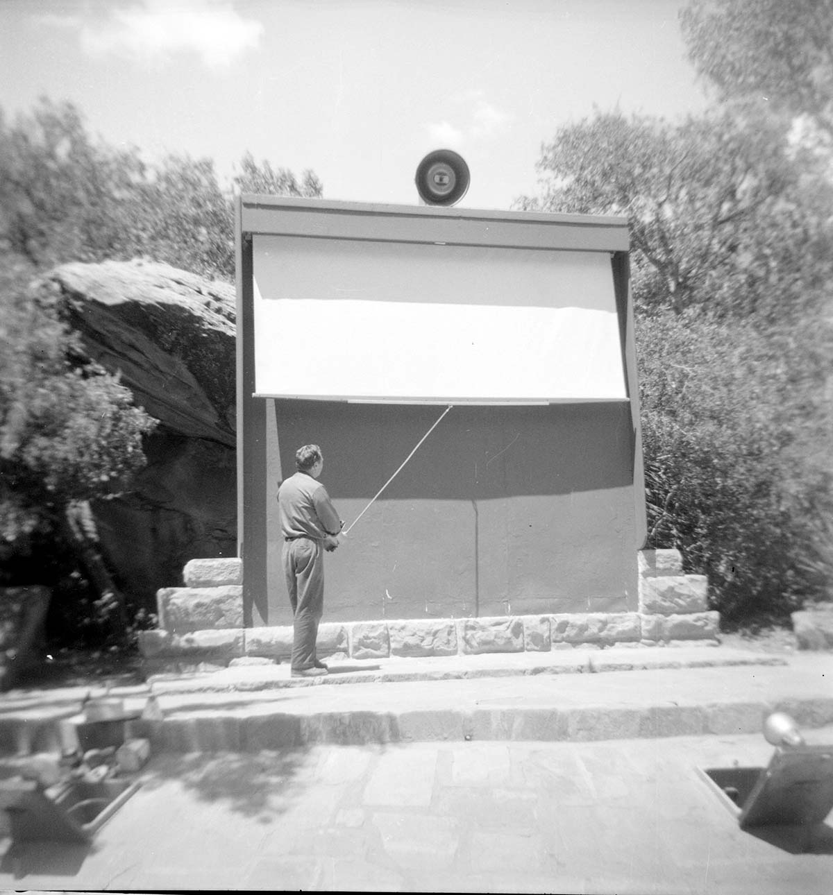 Man standing in front of the South Campground Amphitheater screen and projector.