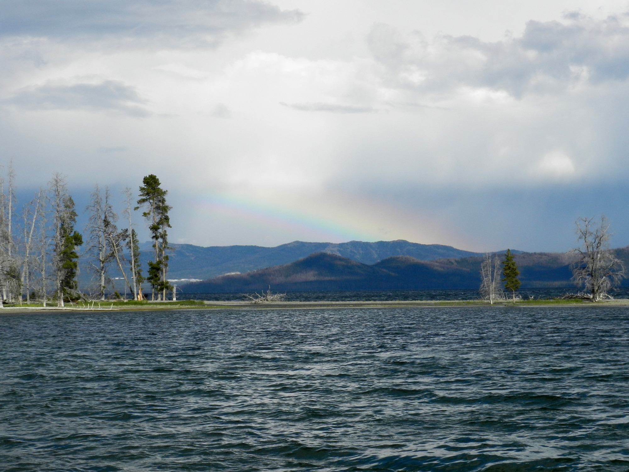 Looking across a choppy lake at clouds and a rainbow