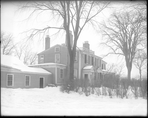 Black and white photograph of large house in the snow.