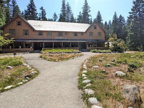 Several paved stone-lined paths lead to a large, symmetrical, two-story toffee-colored building with a wide front porch.