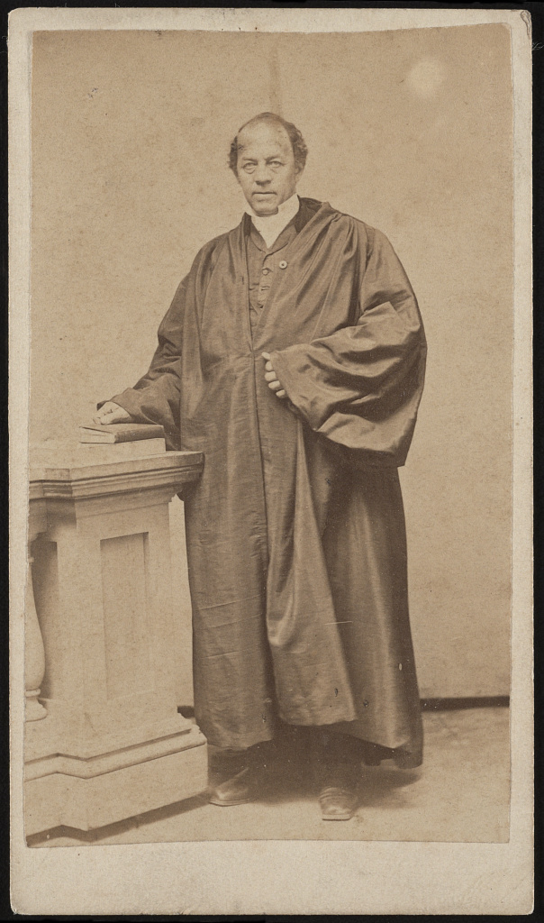 Photograph shows portrait of Rev. Grimes in church robes with his hand on a book, probably a Bible.