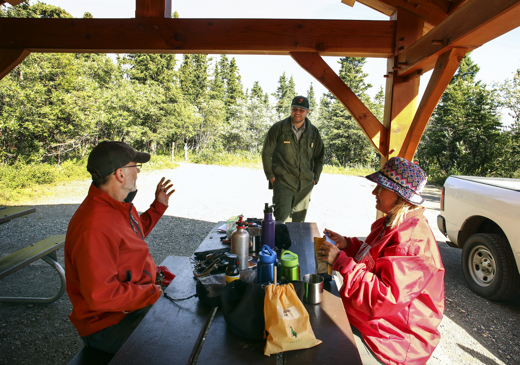 two people at a picnic table speaking to a park ranger
