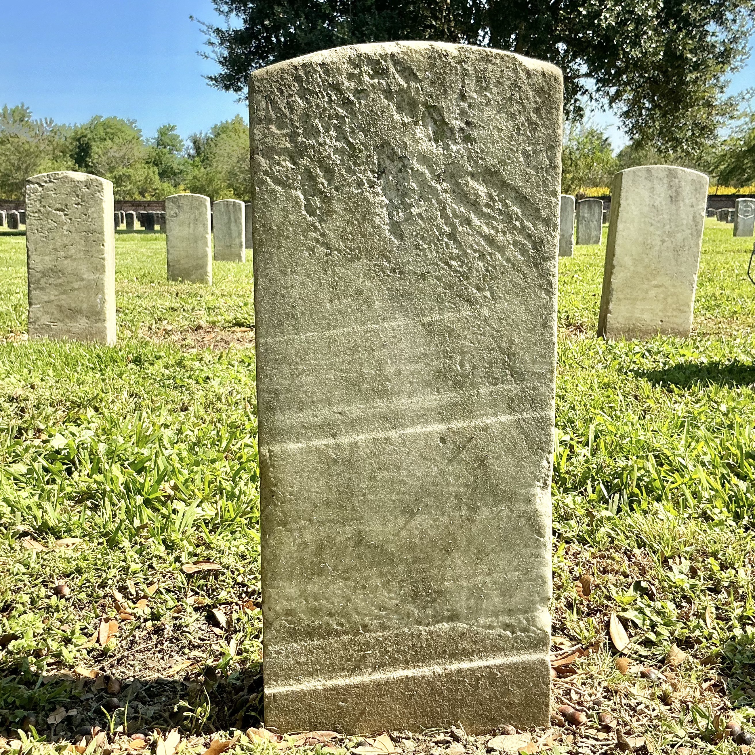Back of historic upright marble headstone with recessed shield face.