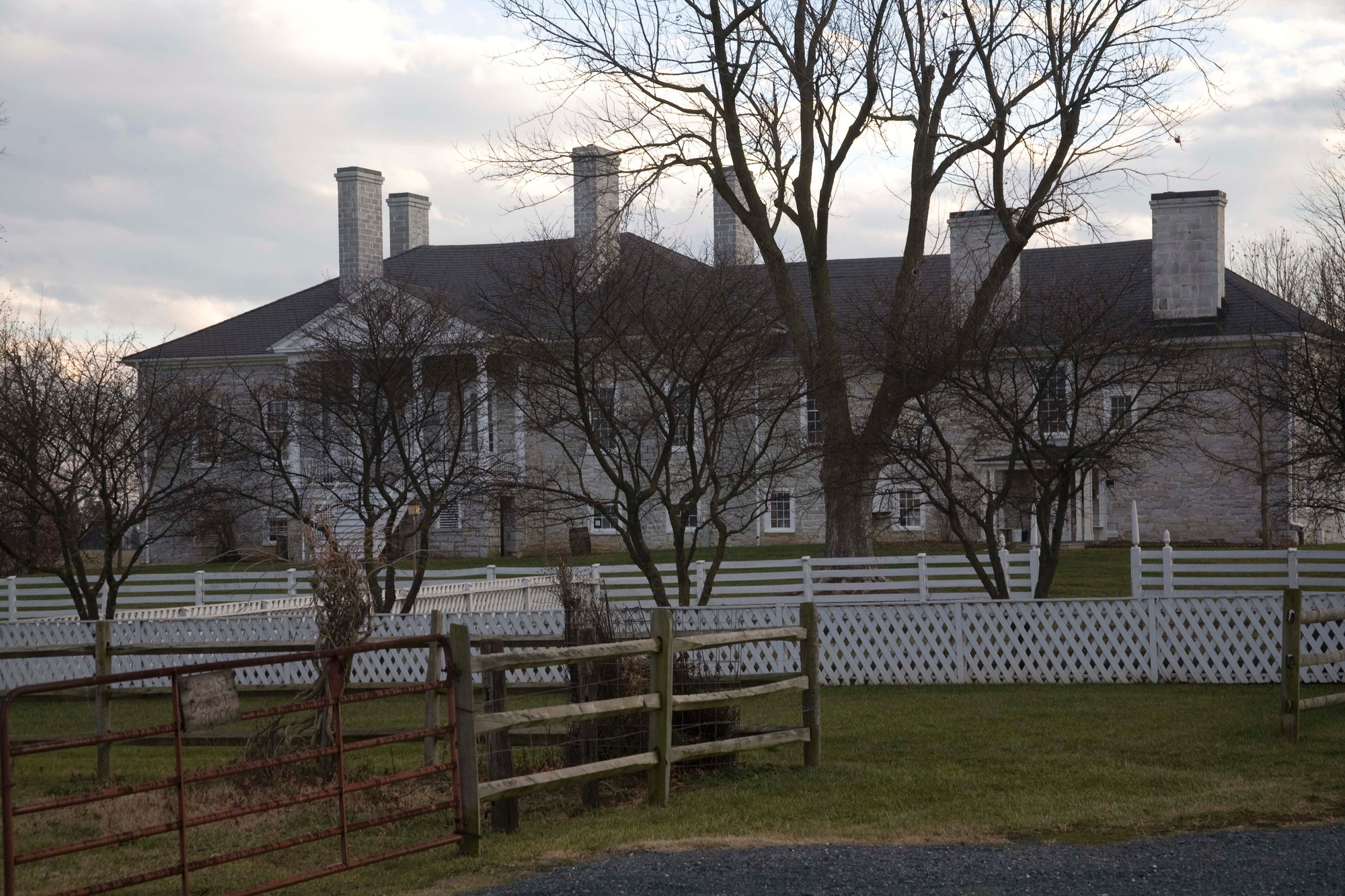 A big house set back behind fences and trees.