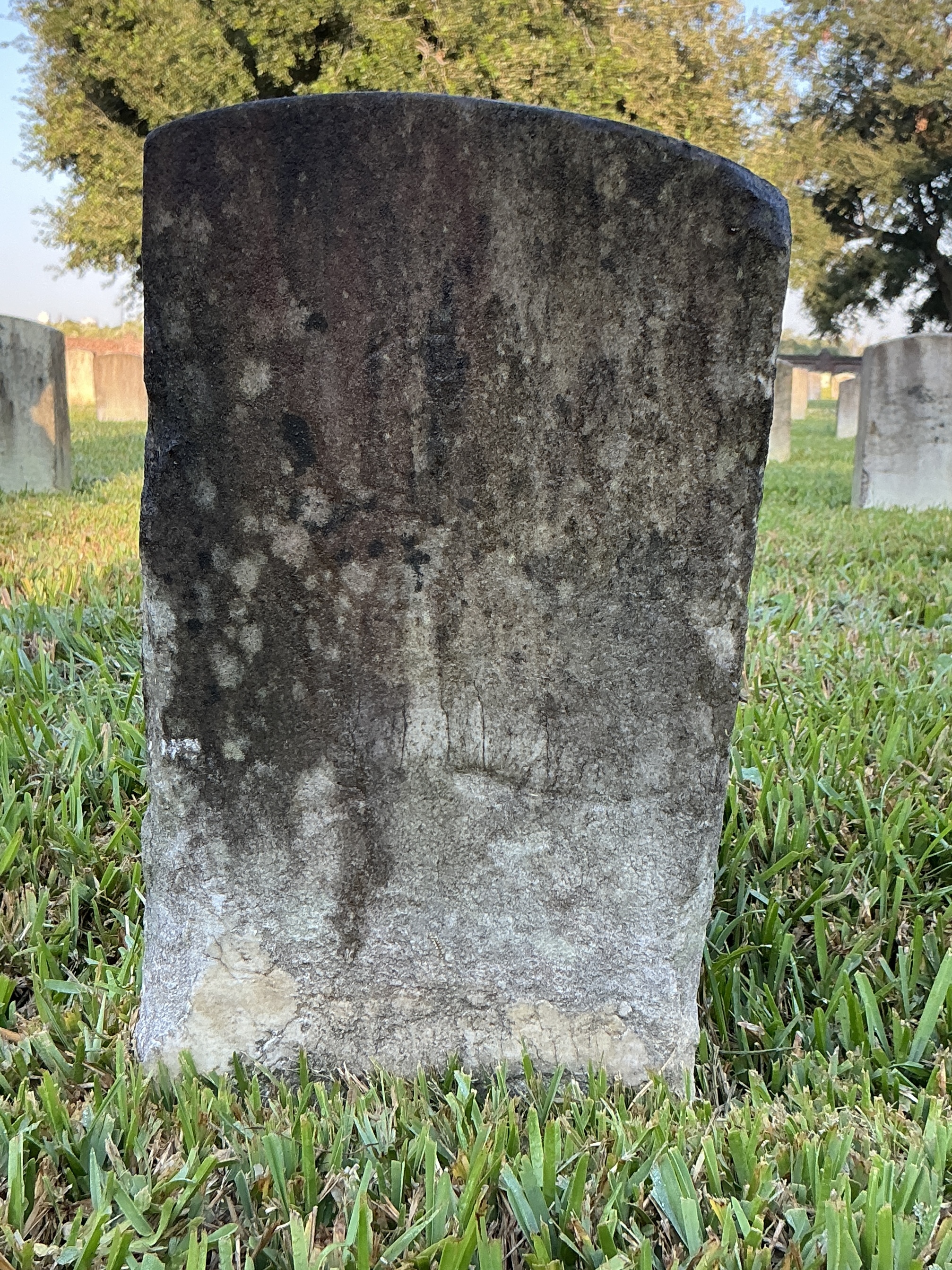 Back of historic upright marble headstone with recessed shield face.