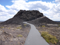 a small, black volcanic cone with a paved trail winding up and around the side