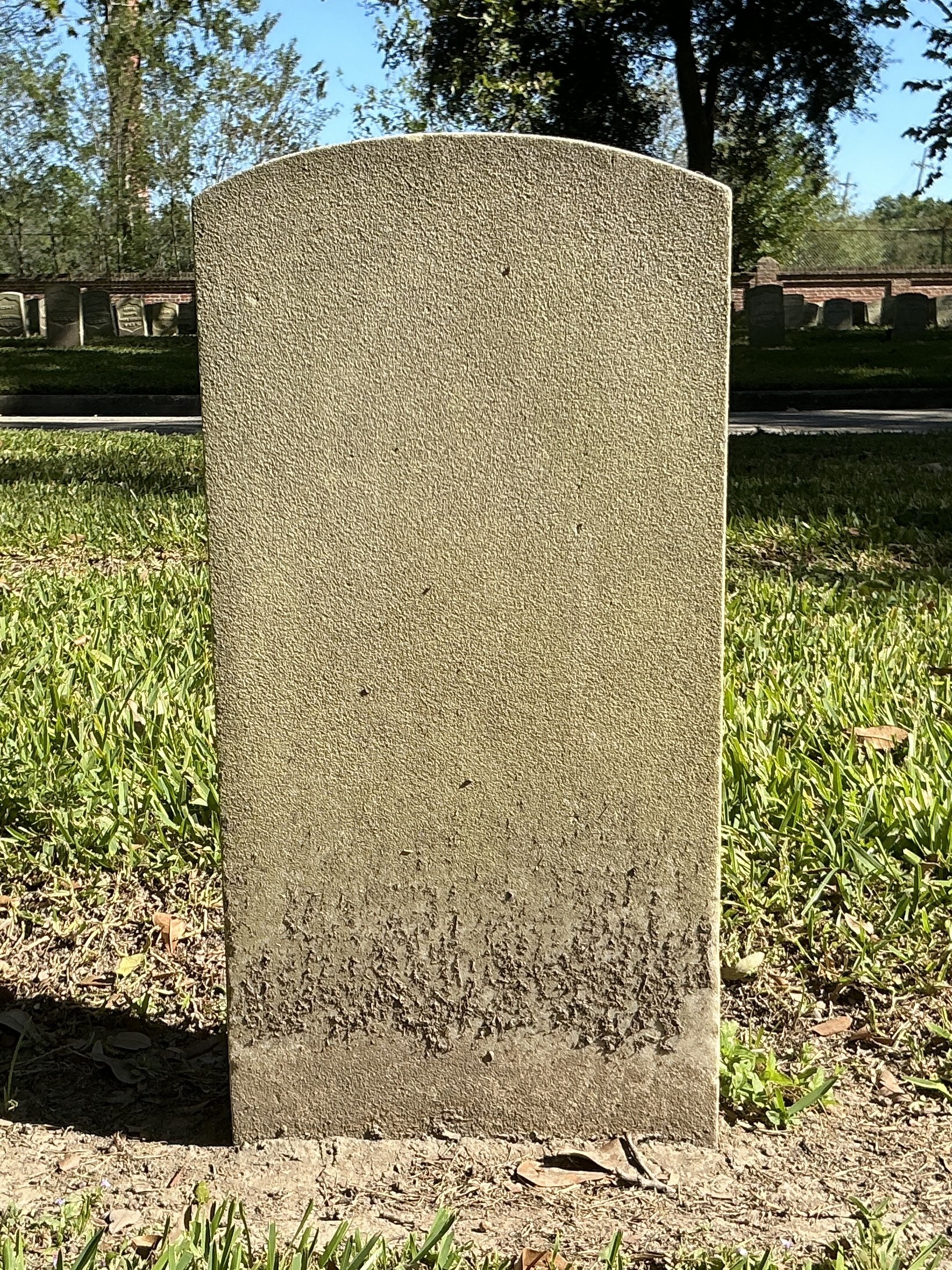 Back of historic upright marble headstone with recessed shield face.