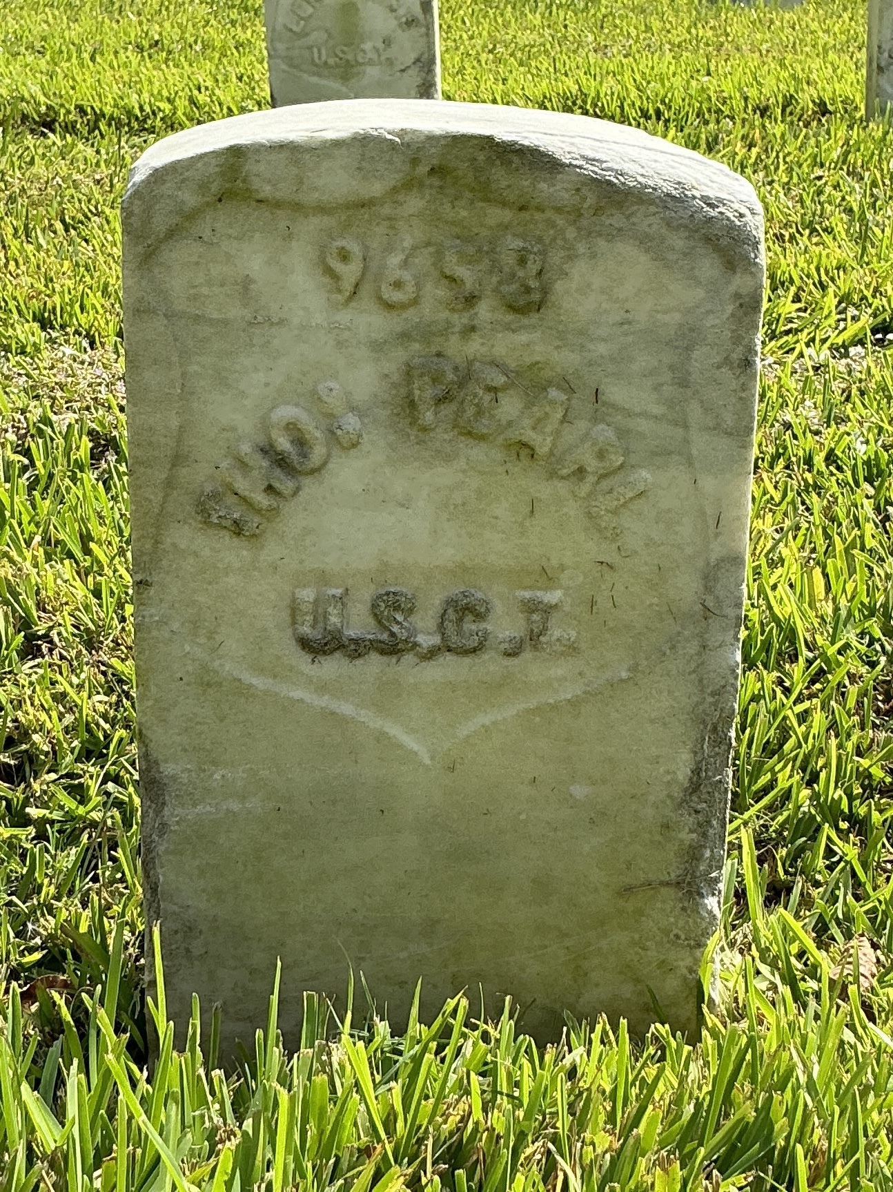Front of historic upright marble headstone with recessed shield face.
