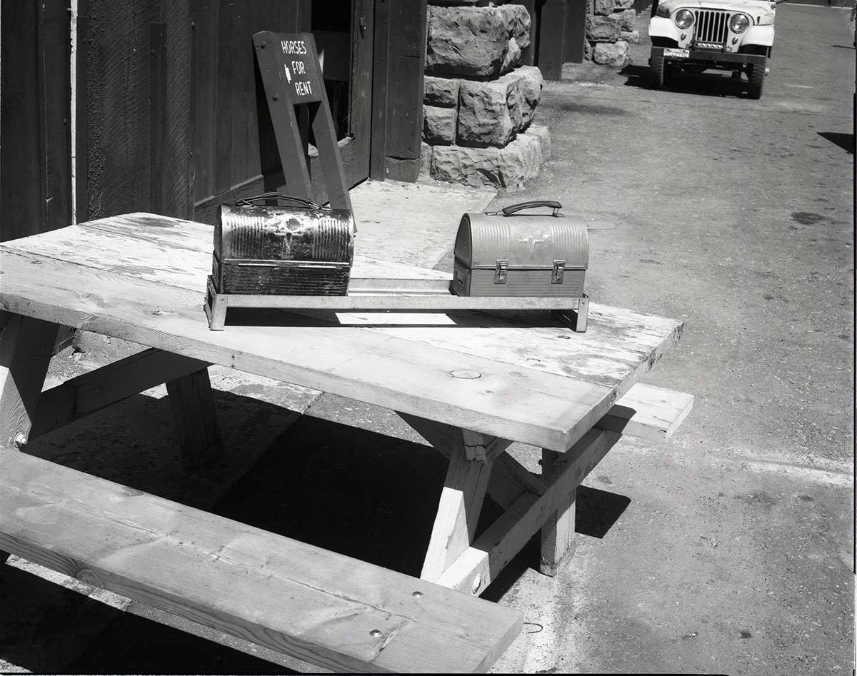 BW Photos of maintenance equipment. Lunch pails in rack on picnic table. Sign in background reads: Horses for Rent.