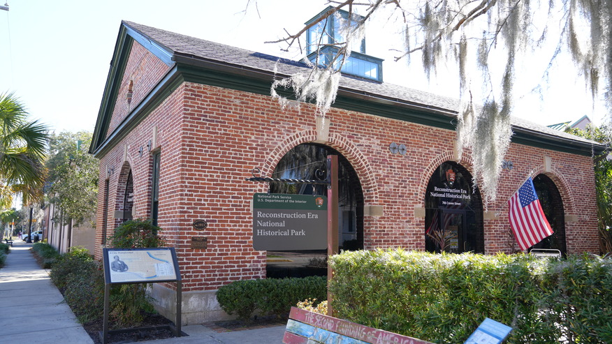 A brick single story building with large arch windows and a cupola.
