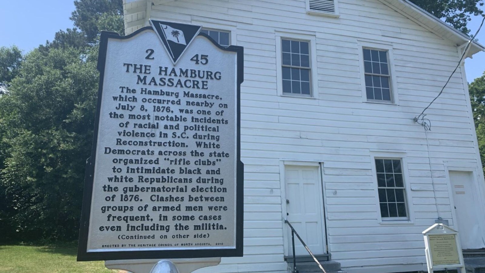 A historic marker in front of a large three-story white building.